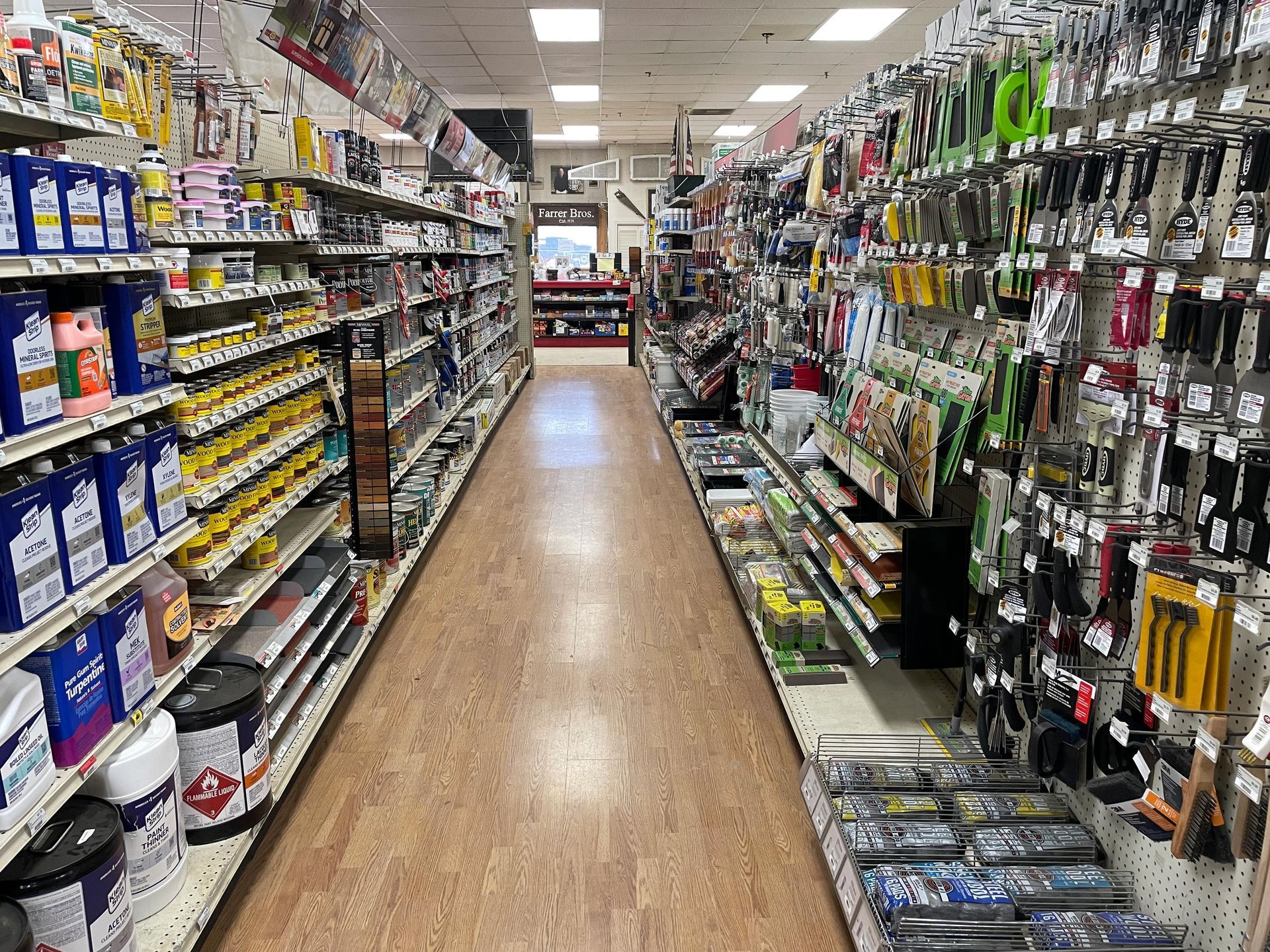 A long aisle of a hardware store filled with lots of products.