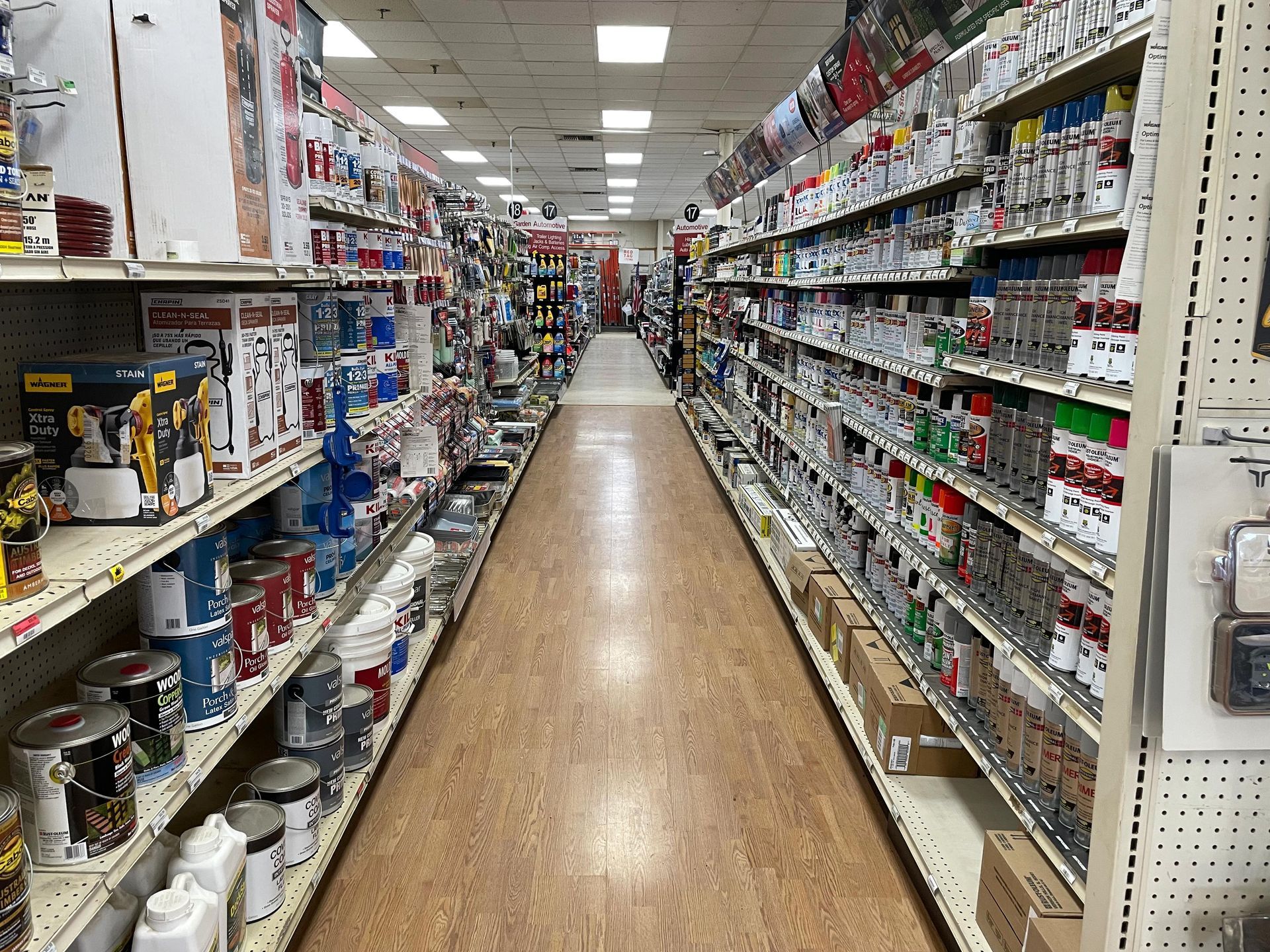 A long aisle of a hardware store filled with lots of products.