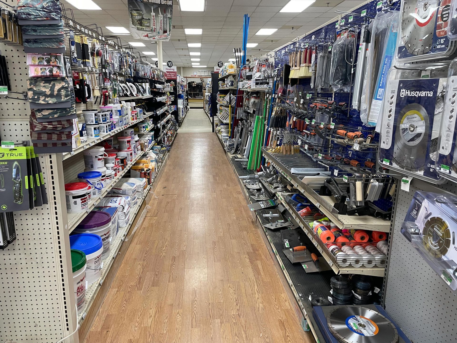 A long aisle of a hardware store filled with lots of shelves.
