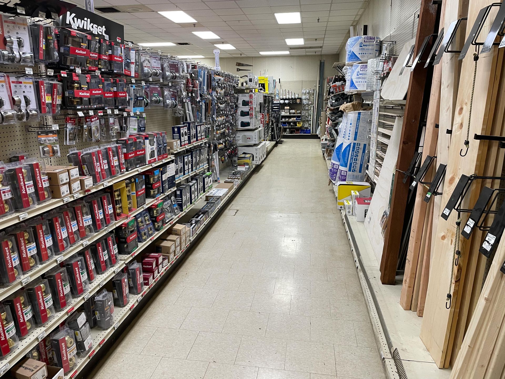 A long aisle of a hardware store filled with lots of shelves.