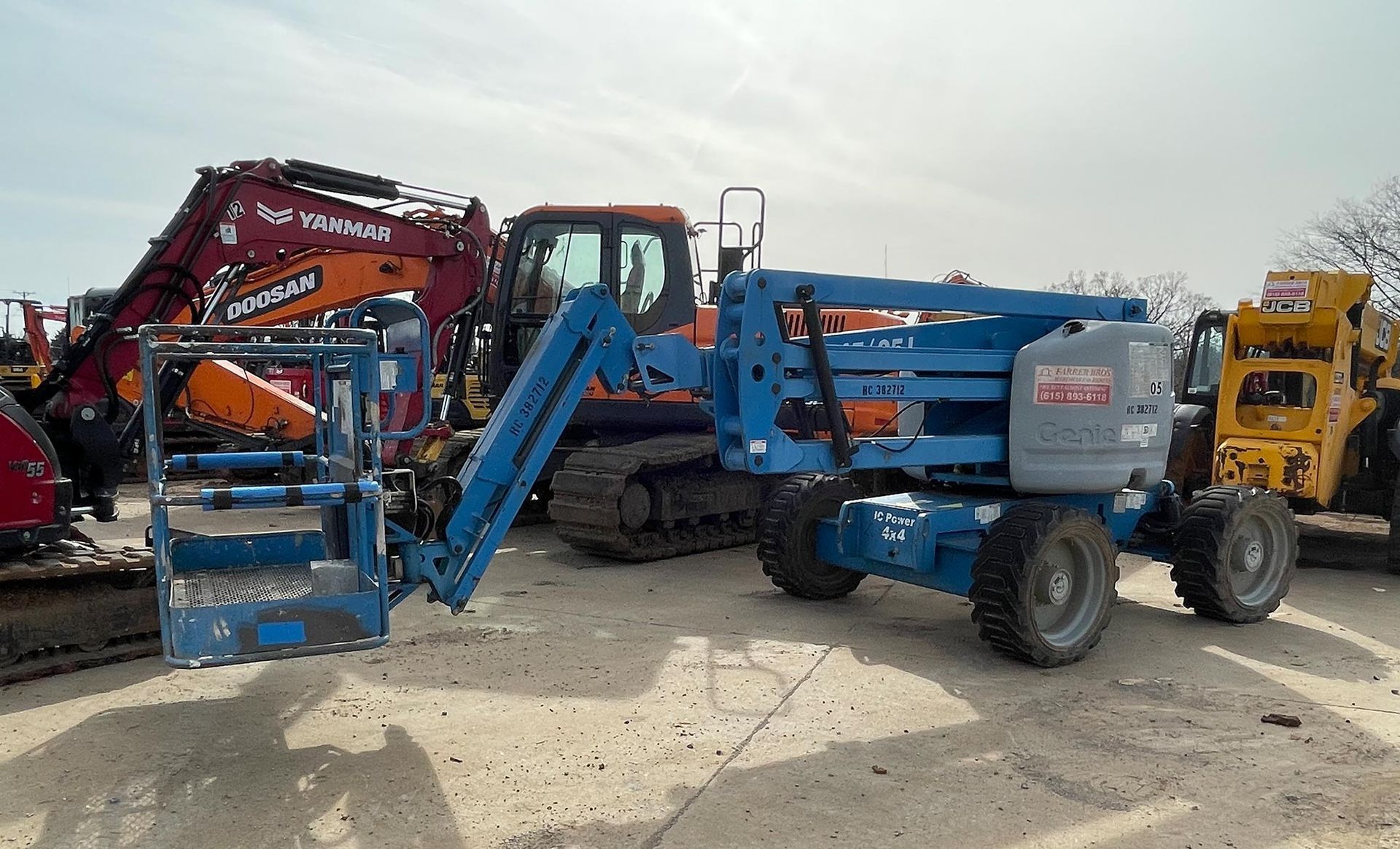 A group of construction vehicles are parked in a parking lot.