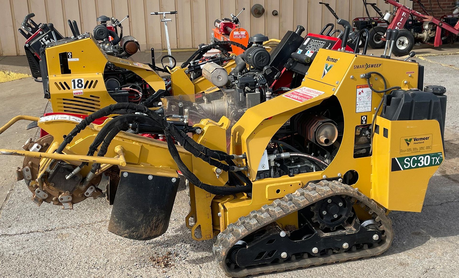 A yellow tractor is parked next to a row of other tractors.