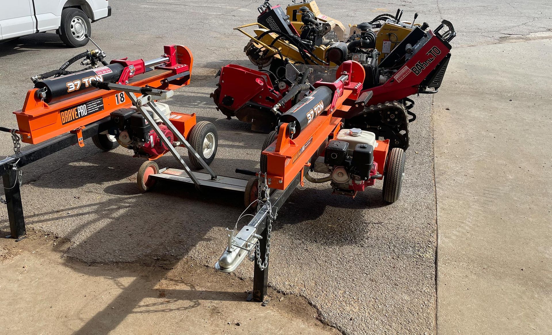 A group of log splitter trailers are sitting on the side of the road.