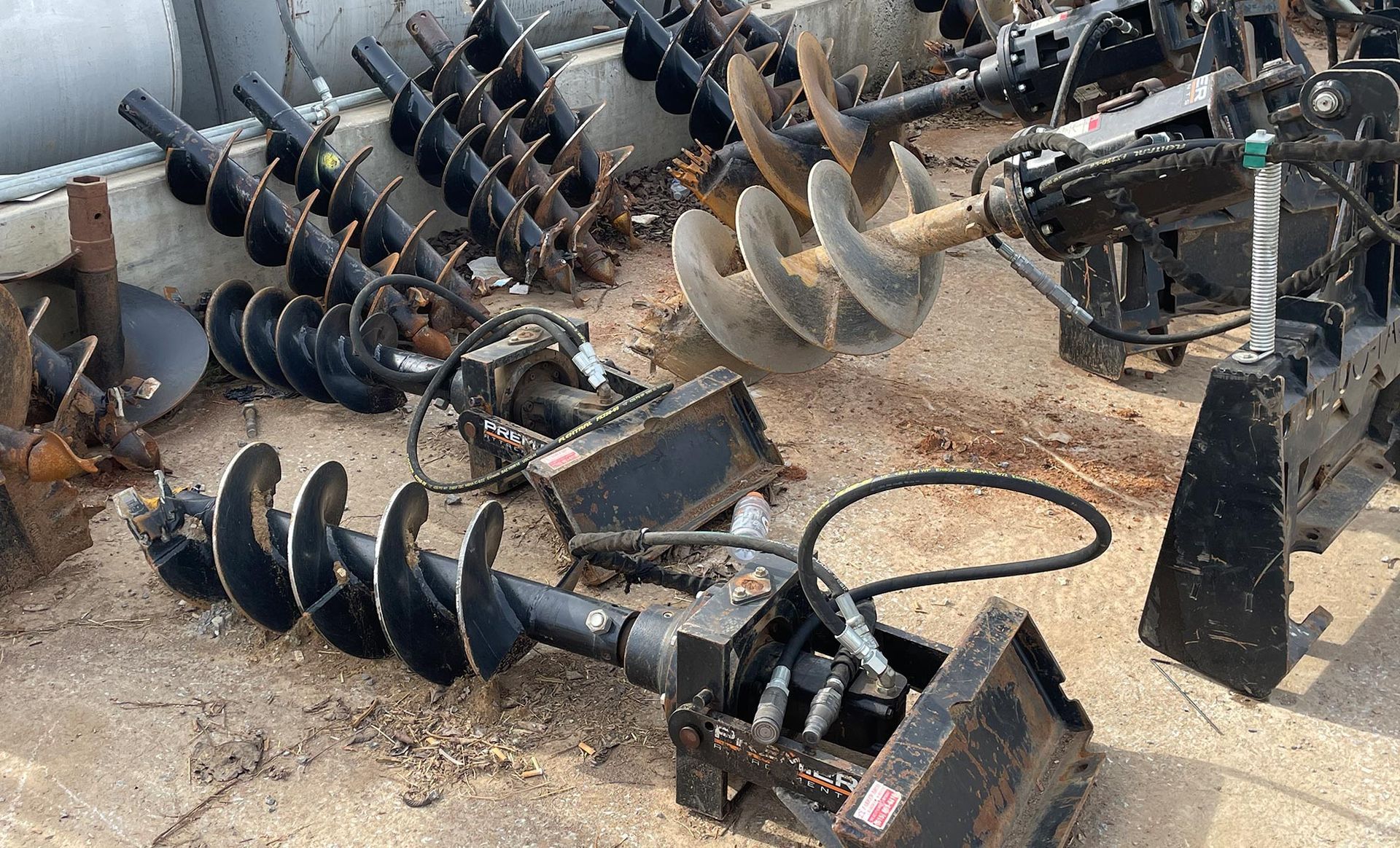 A bunch of drill bits are sitting on the ground.