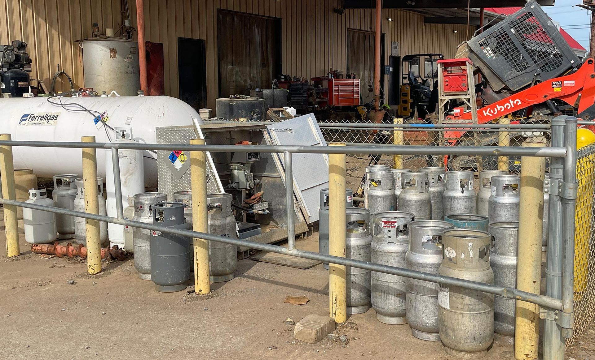 A bunch of gas cylinders are behind a metal fence.