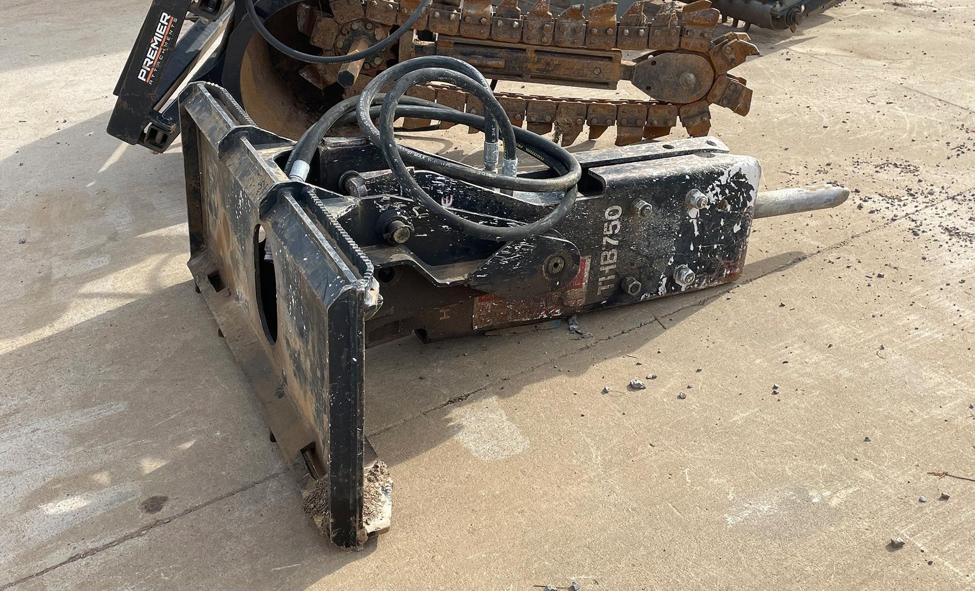 A hydraulic hammer is sitting on the ground next to a bulldozer.