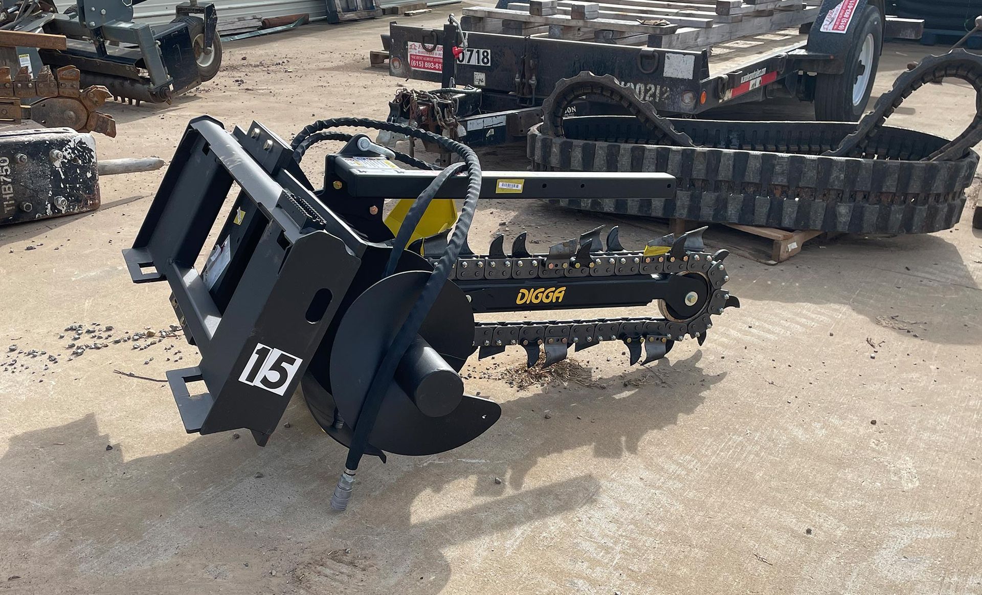 A chainsaw with a bucket attached to it is sitting on the ground.