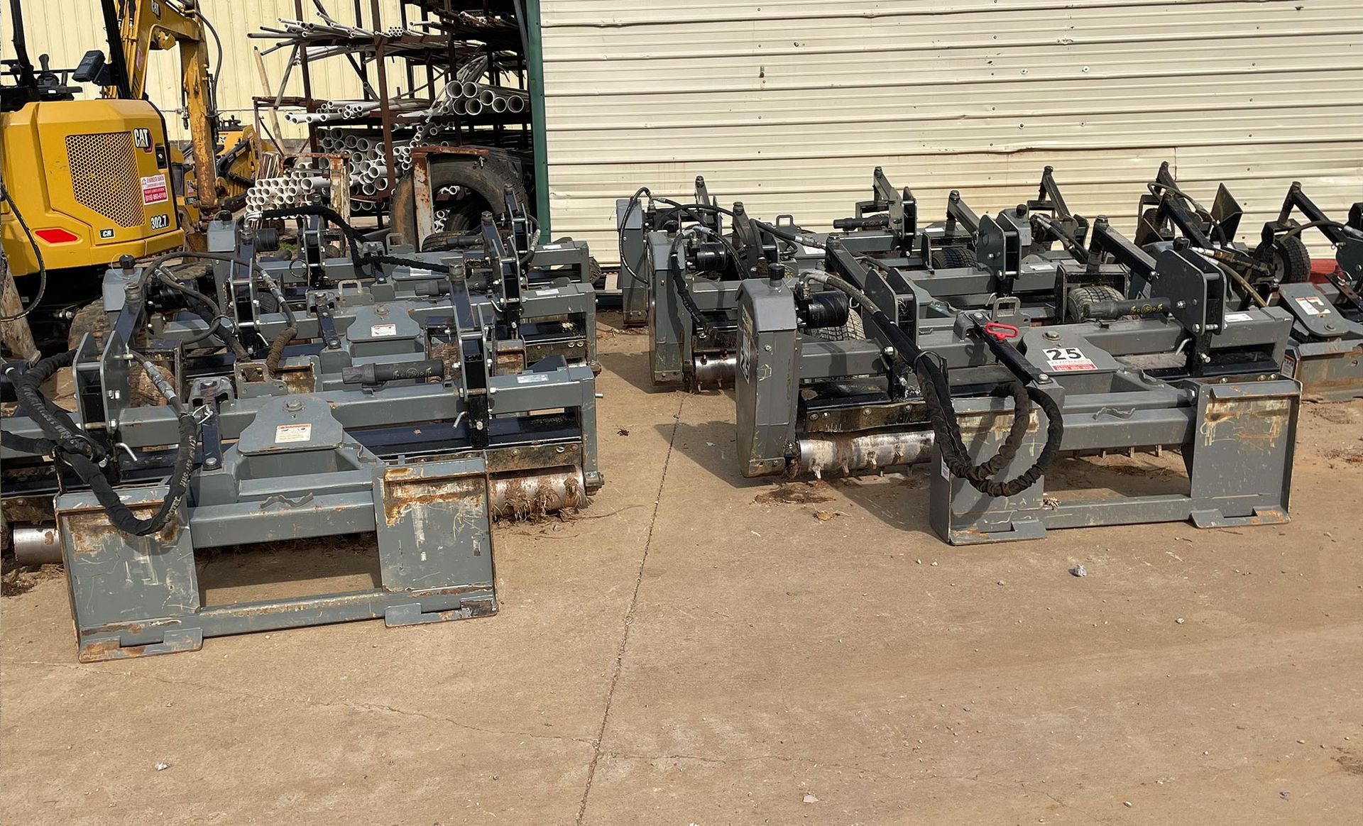 A bunch of tractors are parked in a lot in front of a building.