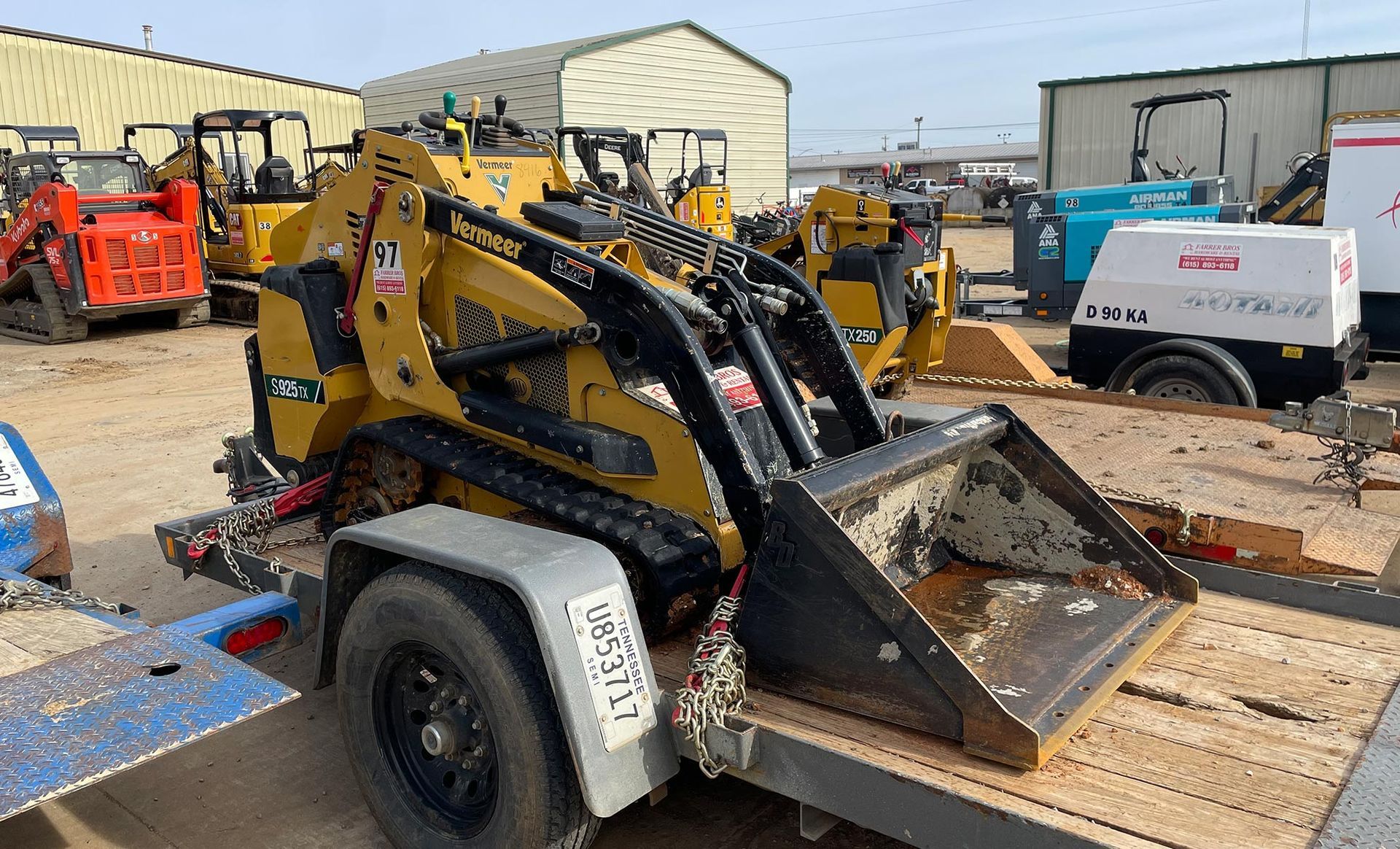 A small loader is sitting on top of a trailer.