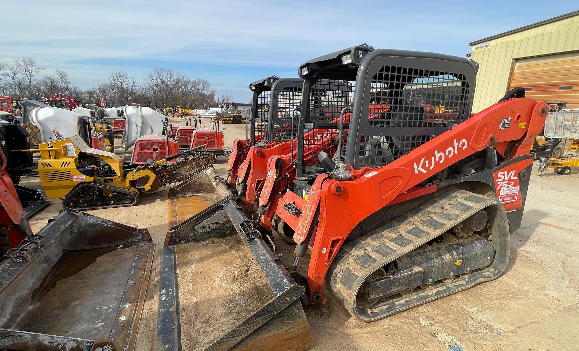 A red bulldozer is parked in a lot next to a building.