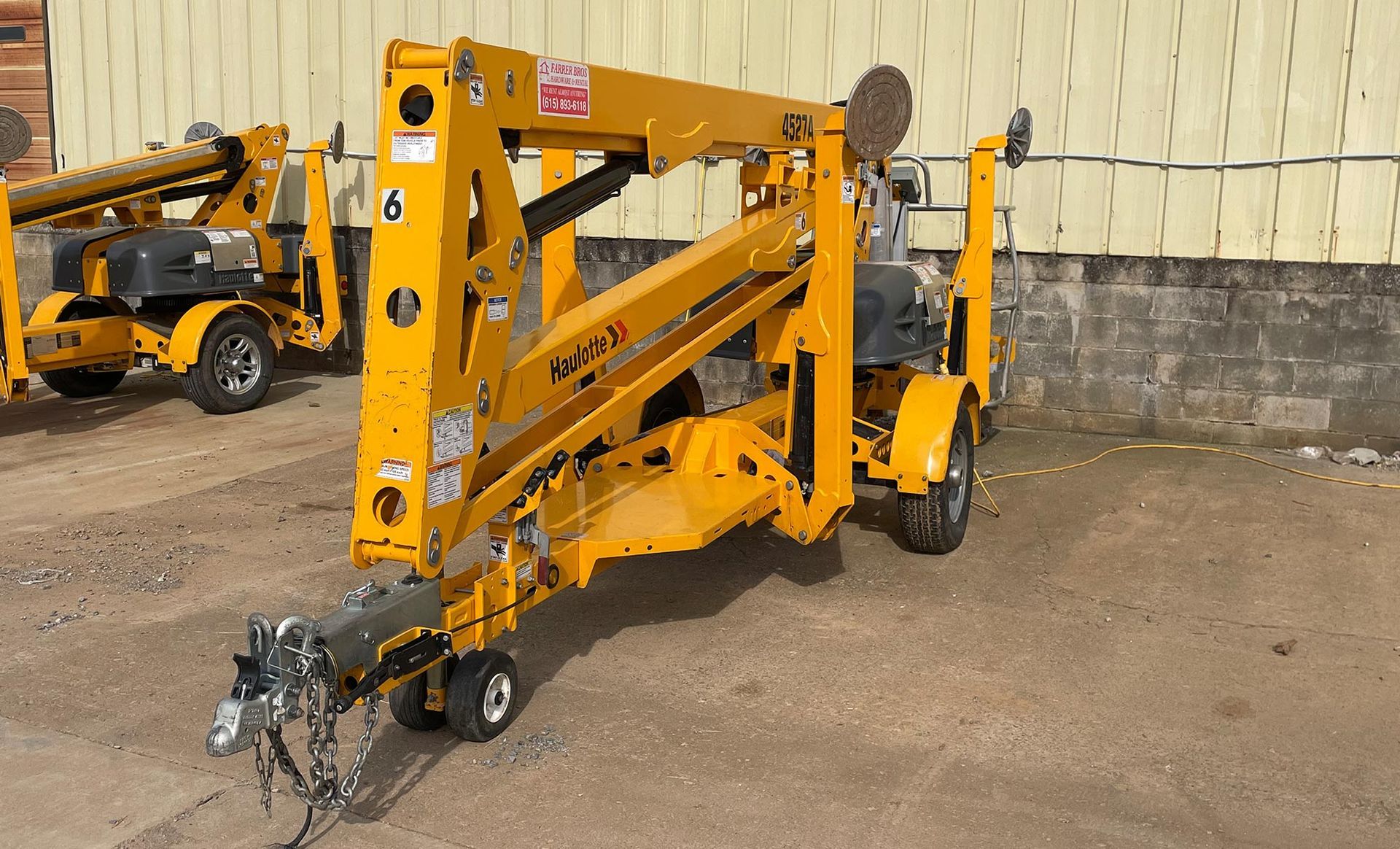 A yellow crane is parked in front of a building.