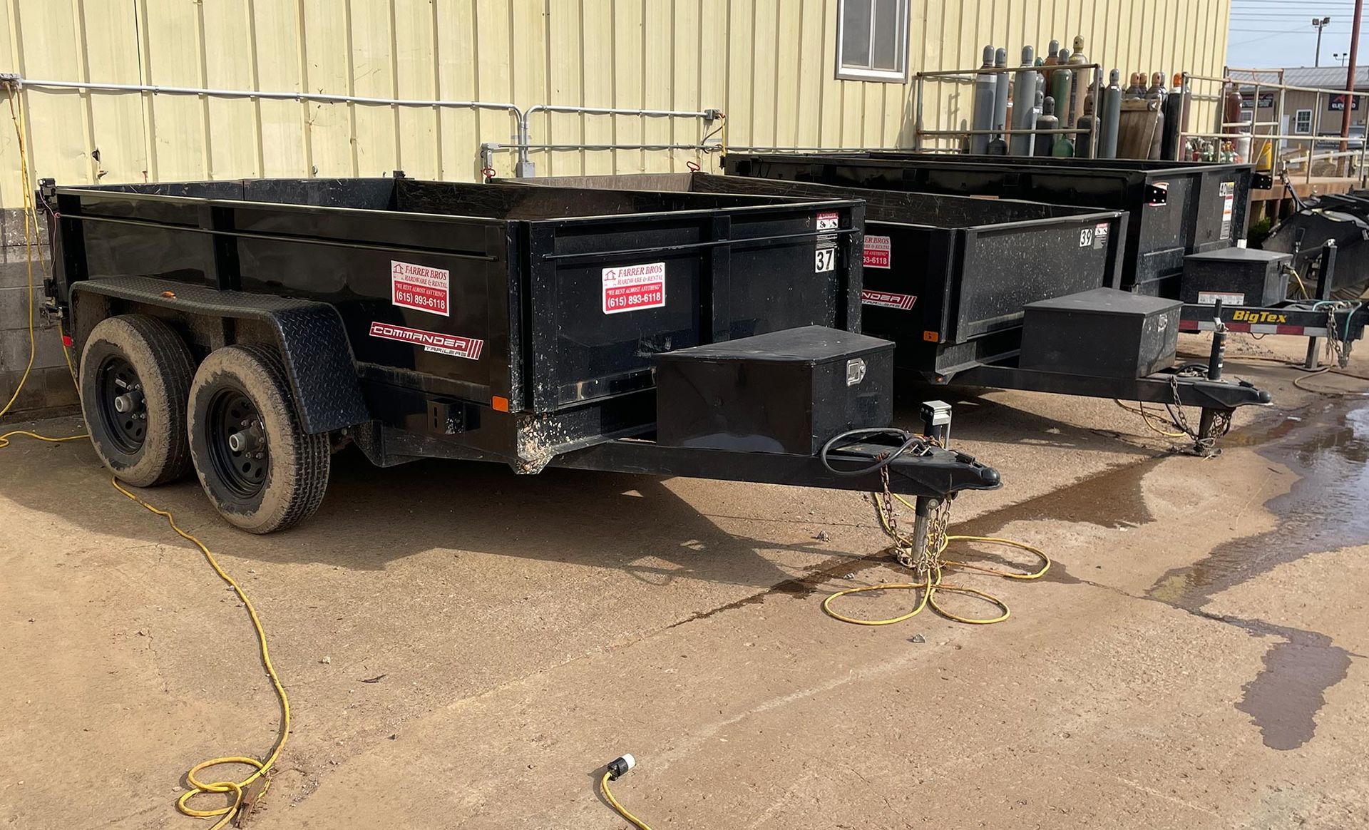 A row of dump trailers are parked in front of a building.