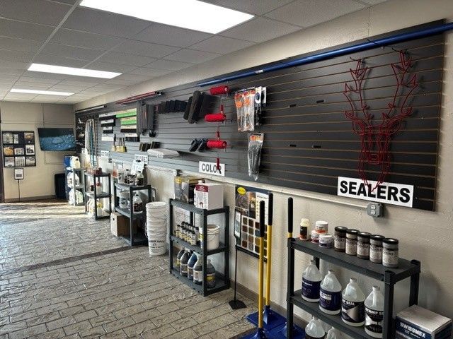 Hardware store aisle with shelves of sealants, tools, and supplies under bright ceiling lights