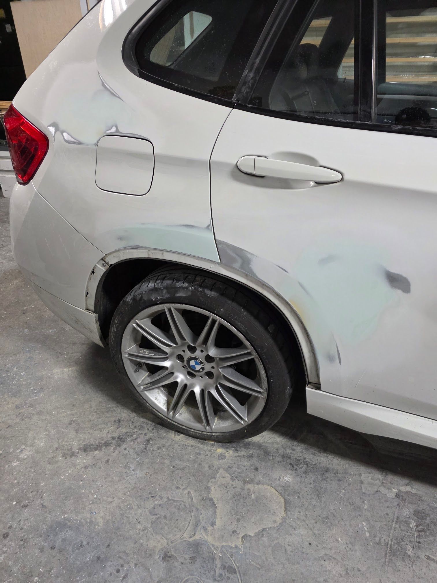 Rear side of a white SUV with dents and scratches near the wheel and fuel door