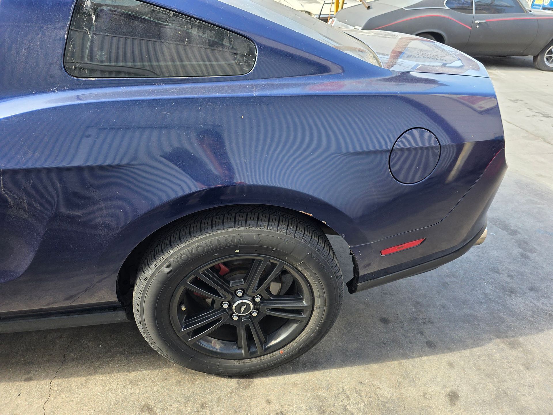 Blue sports car rear side with black wheel parked outdoors on pavement