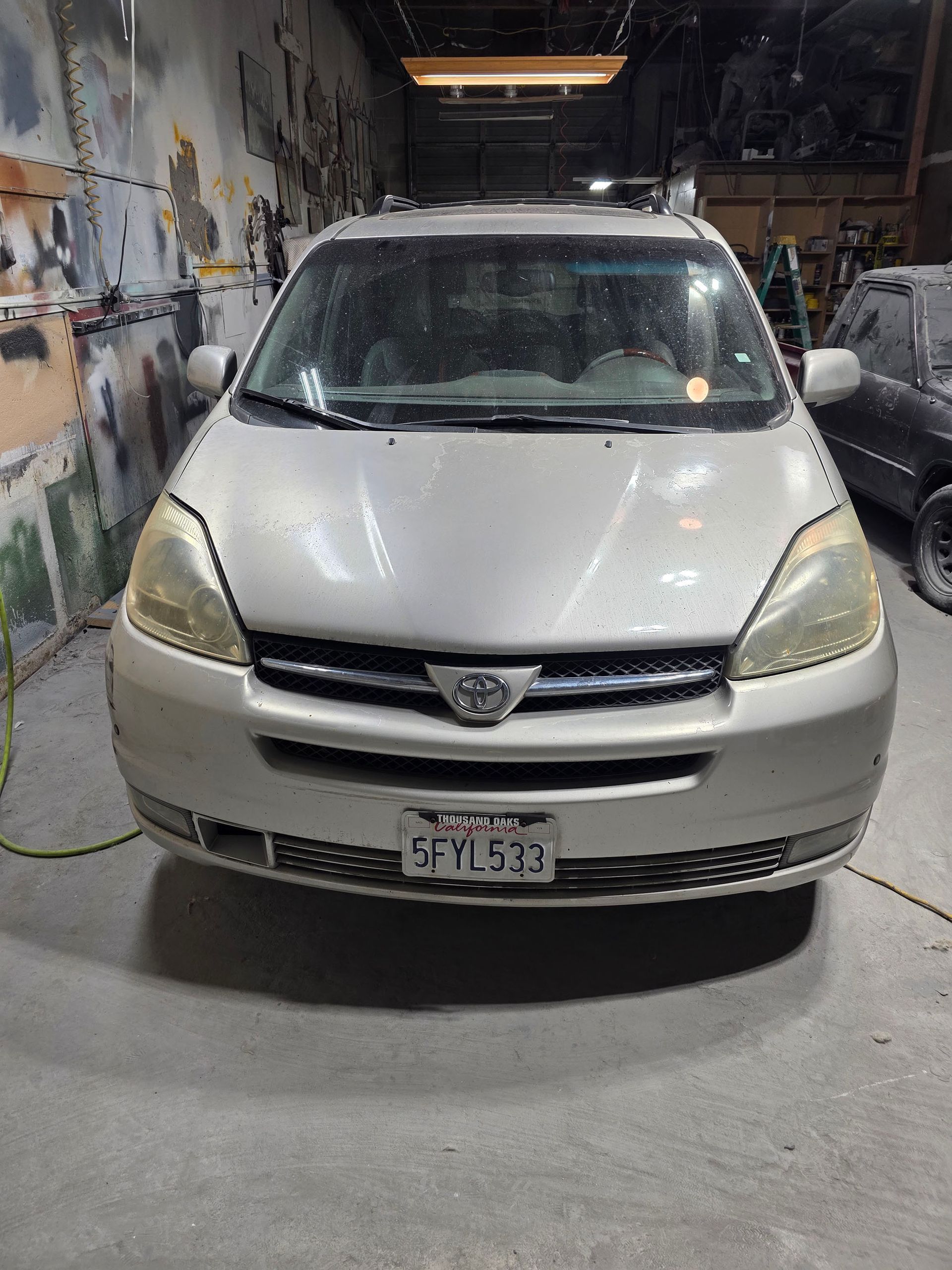 Front view of a silver Peugeot hatchback parked inside a workshop garage.