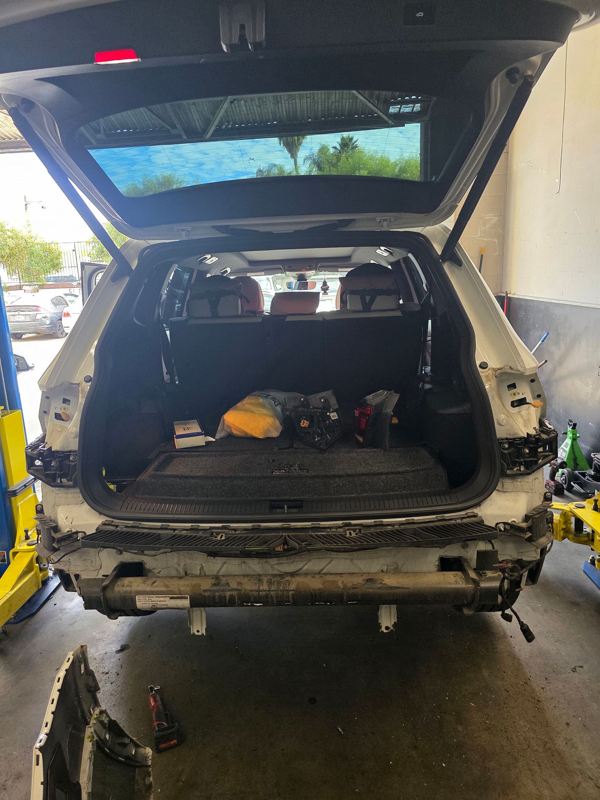 SUV with rear hatch open in a garage, rear bumper removed and tools inside cargo area.