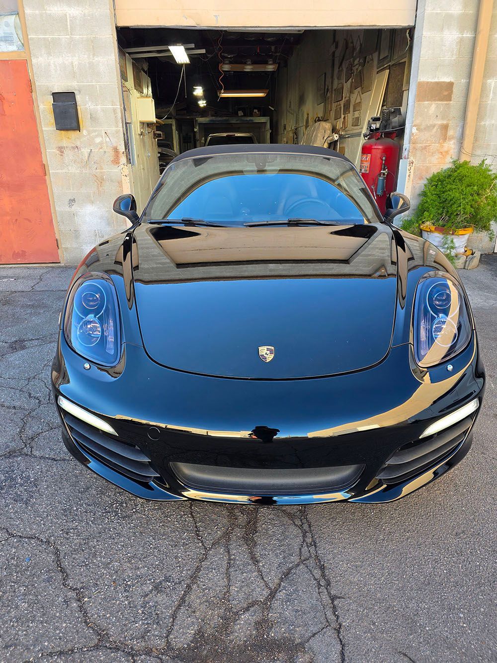 Black Porsche sports car parked in front of an open garage.