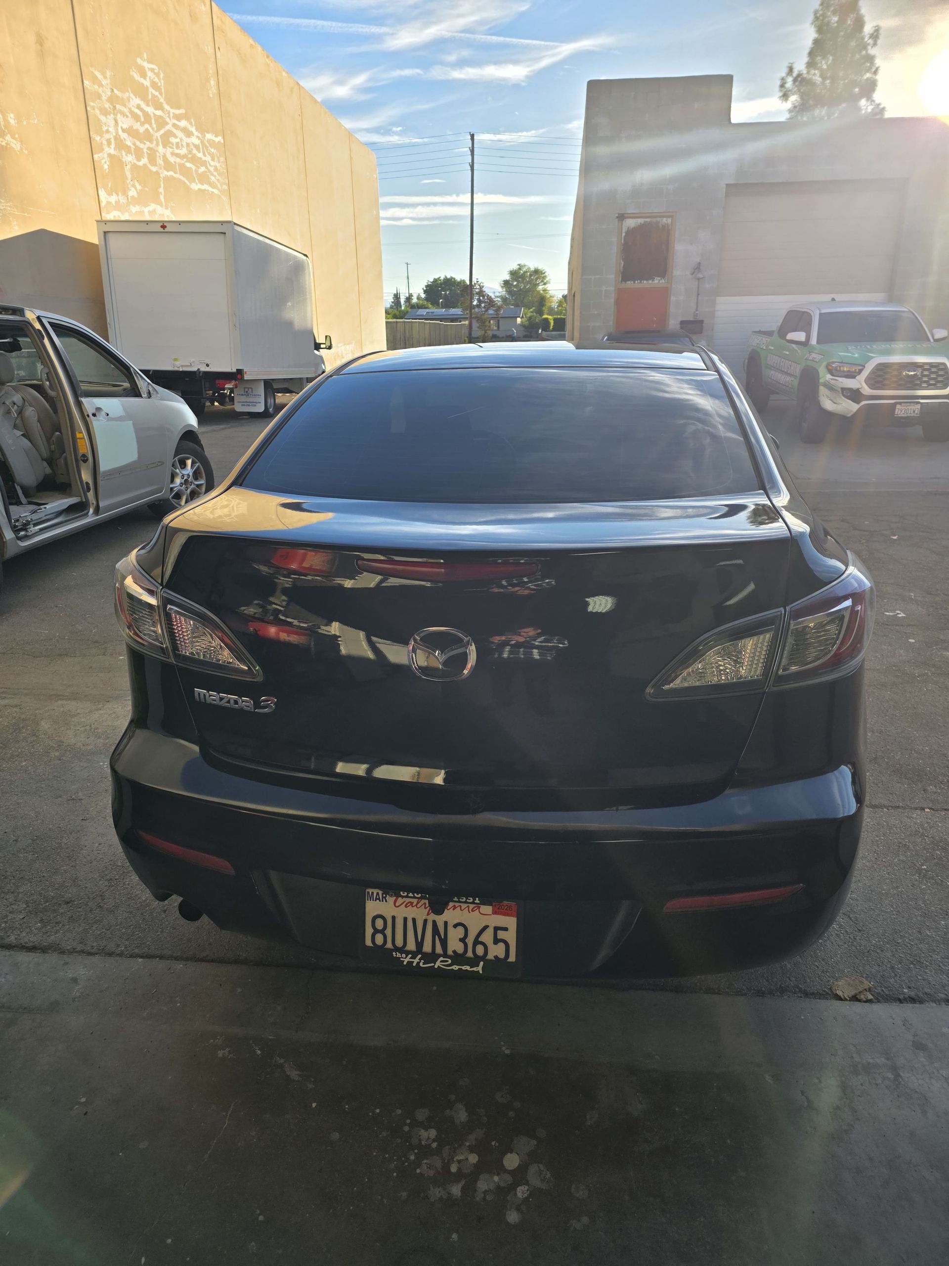 Black sedan parked in a lot, rear view with a visible license plate.