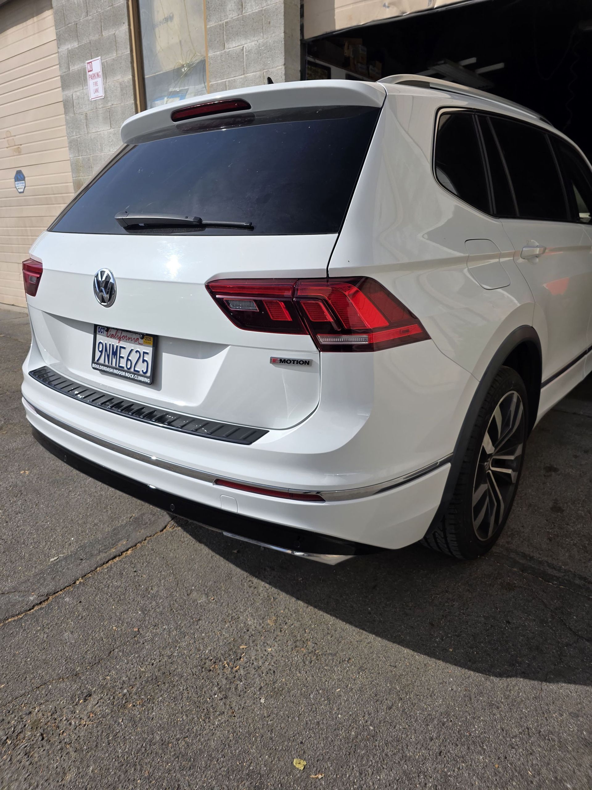 White SUV parked beside a building in an alley, rear view