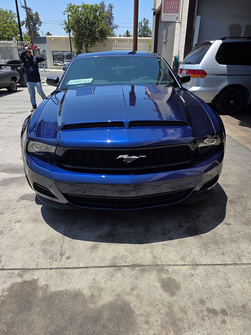 Blue Ford Mustang parked on a sunny street, front view in a driveway or lot