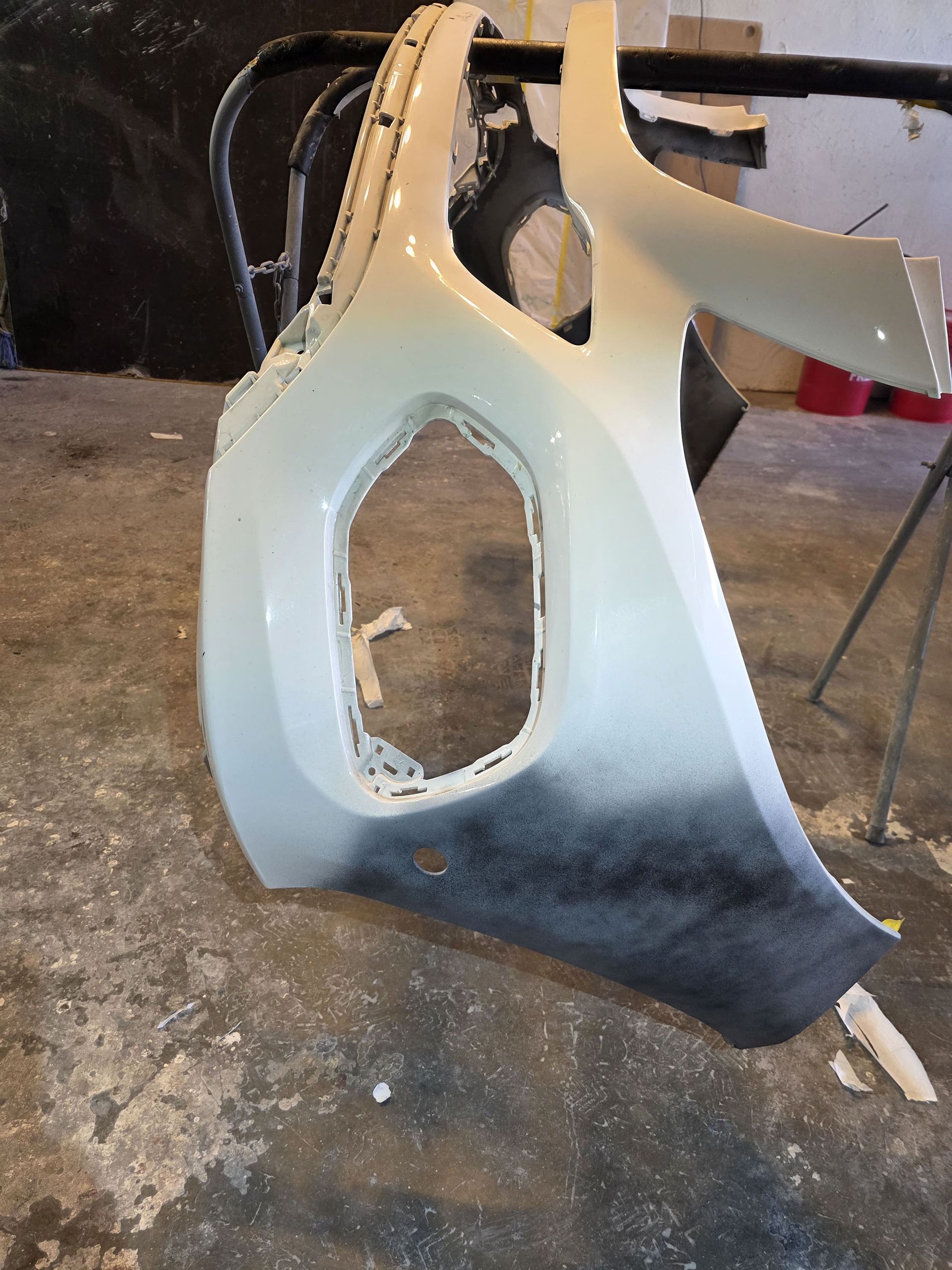 Car bumper cover in white and black, leaning against a wall in a garage