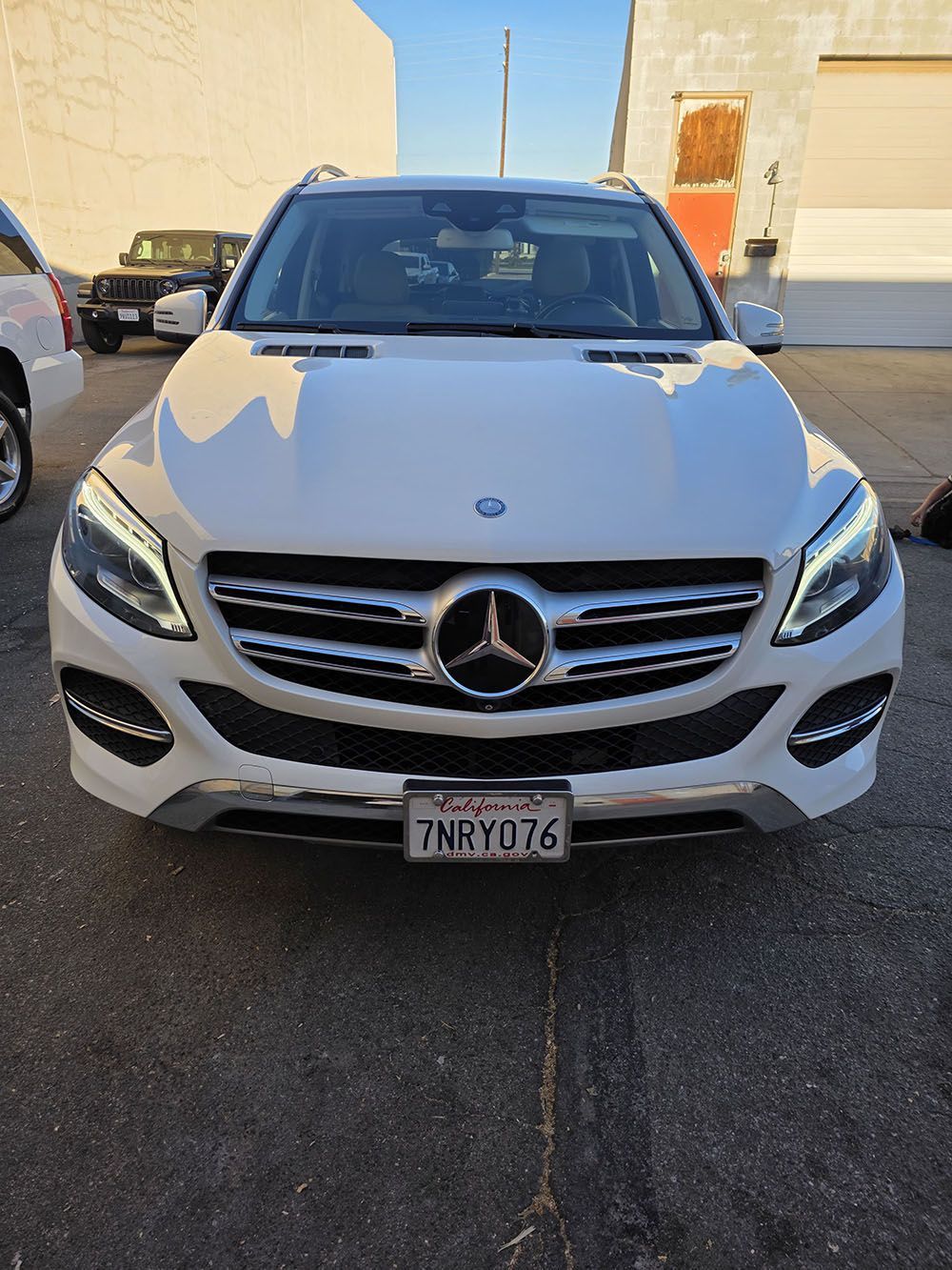 Front view of a white Mercedes SUV parked outdoors in a lot.
