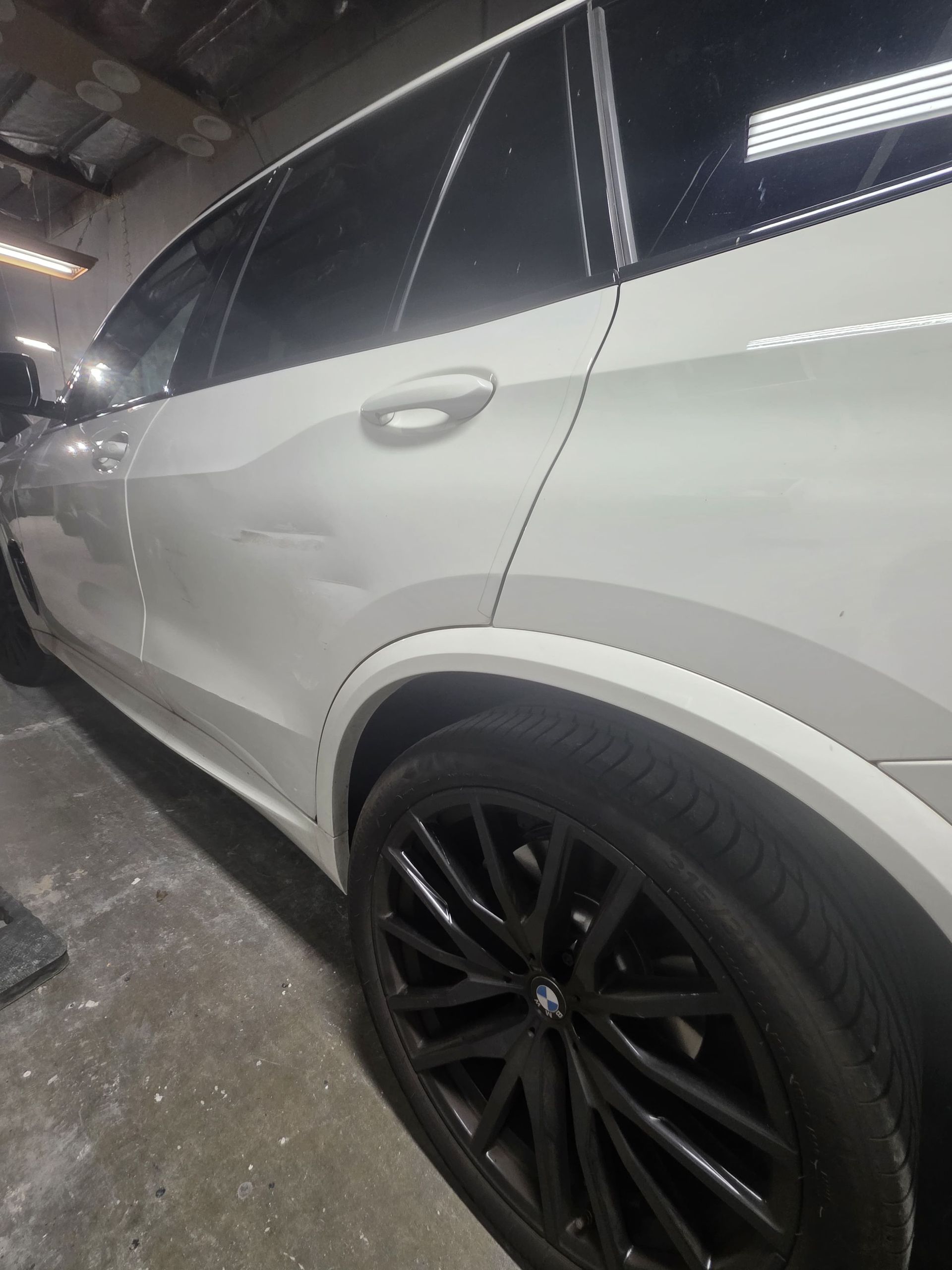 White SUV with black wheels parked in a garage, side view close-up