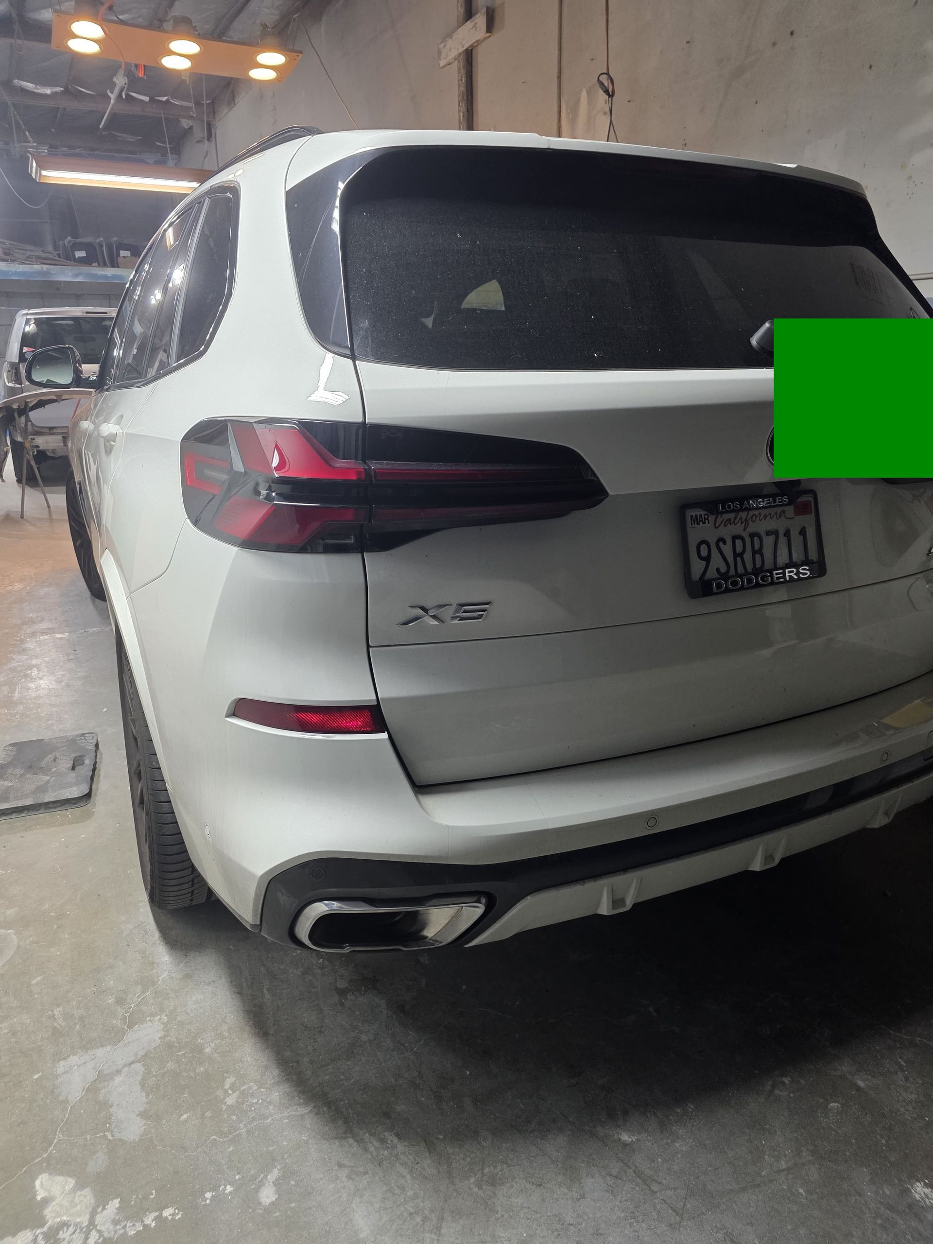 White SUV parked in a concrete garage, rear view with taillights and license plate visible