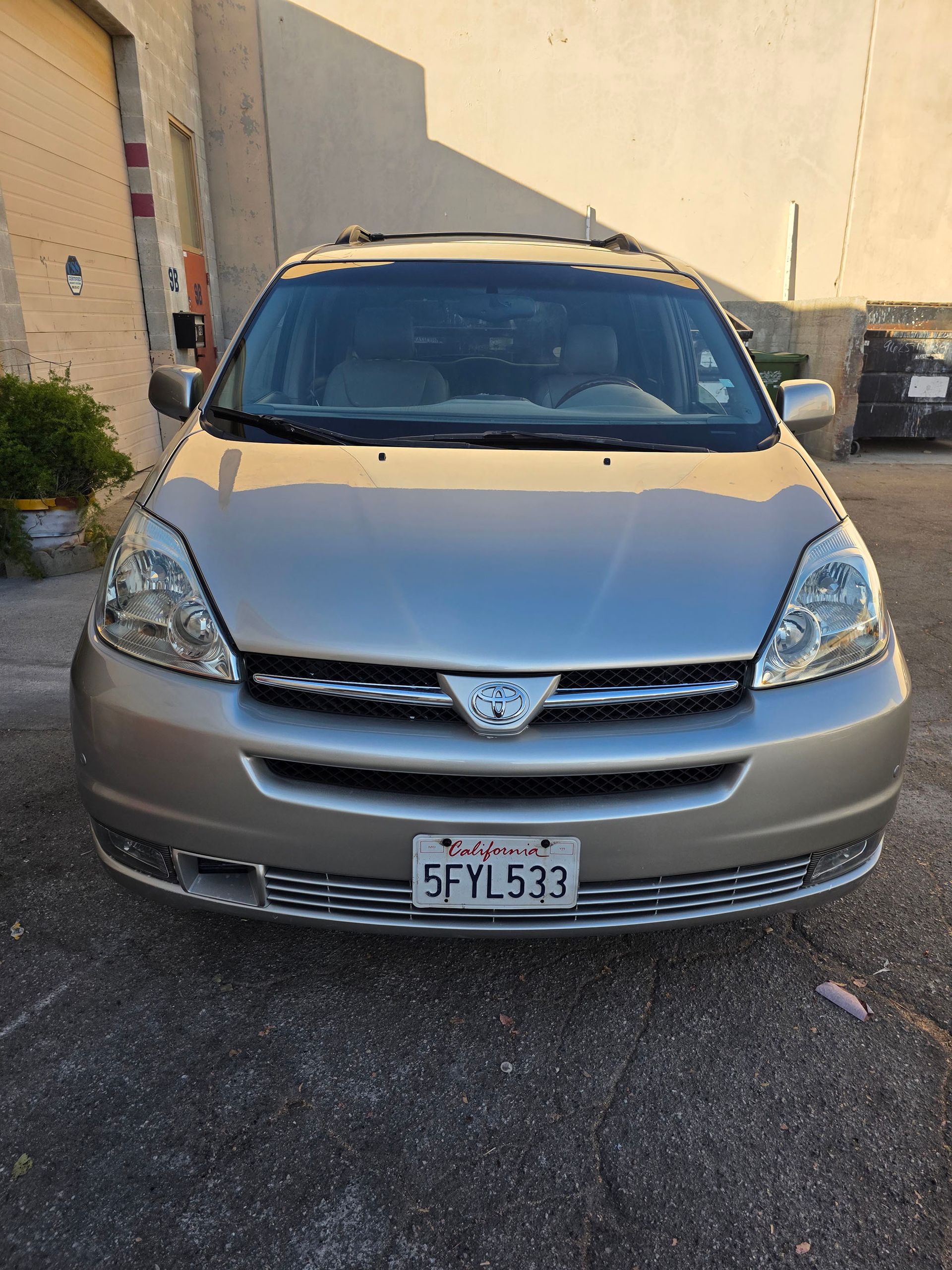 Front view of a beige Toyota sedan parked in a lot beside a building