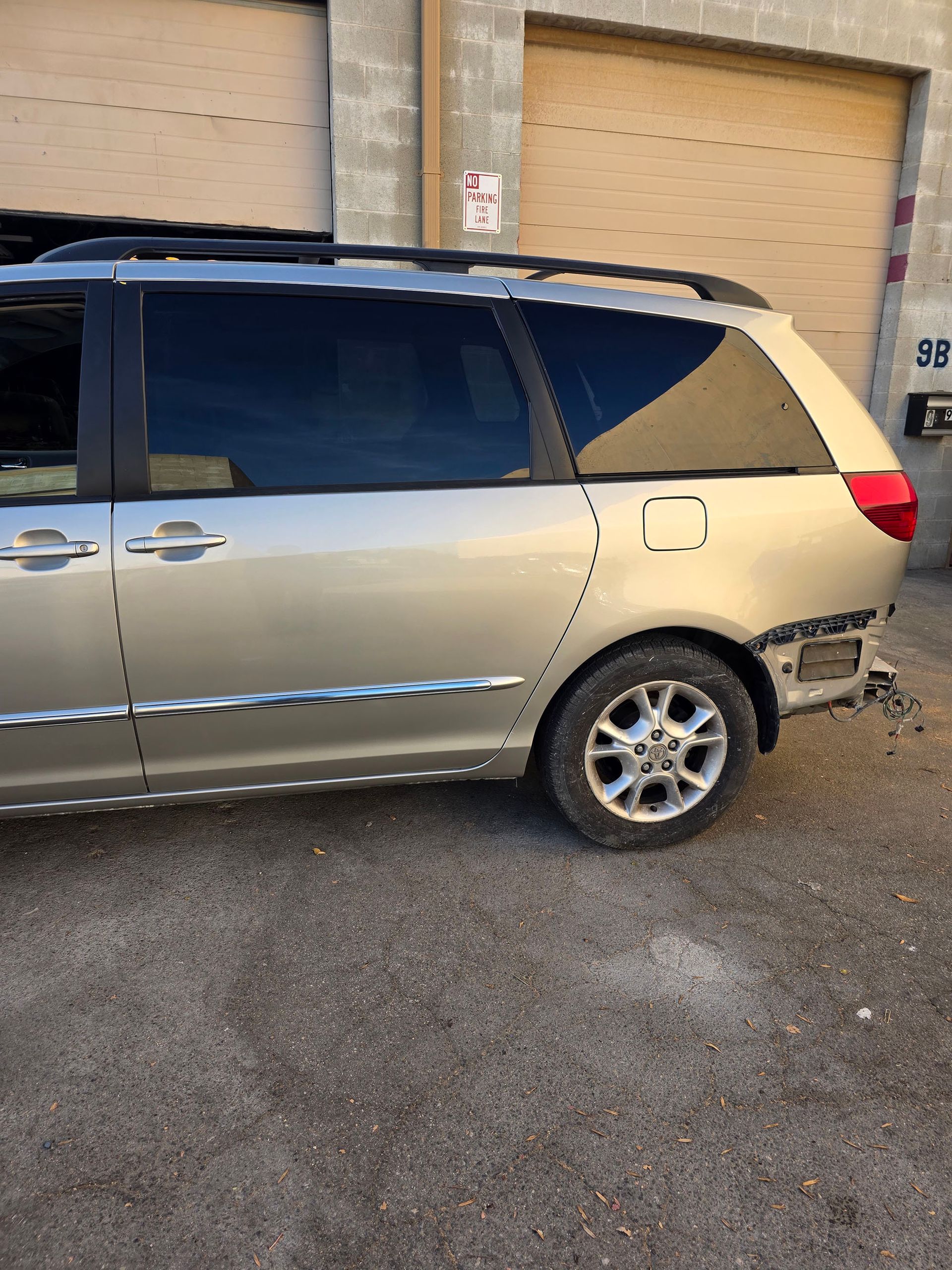 Silver minivan parked by a beige building with garage doors