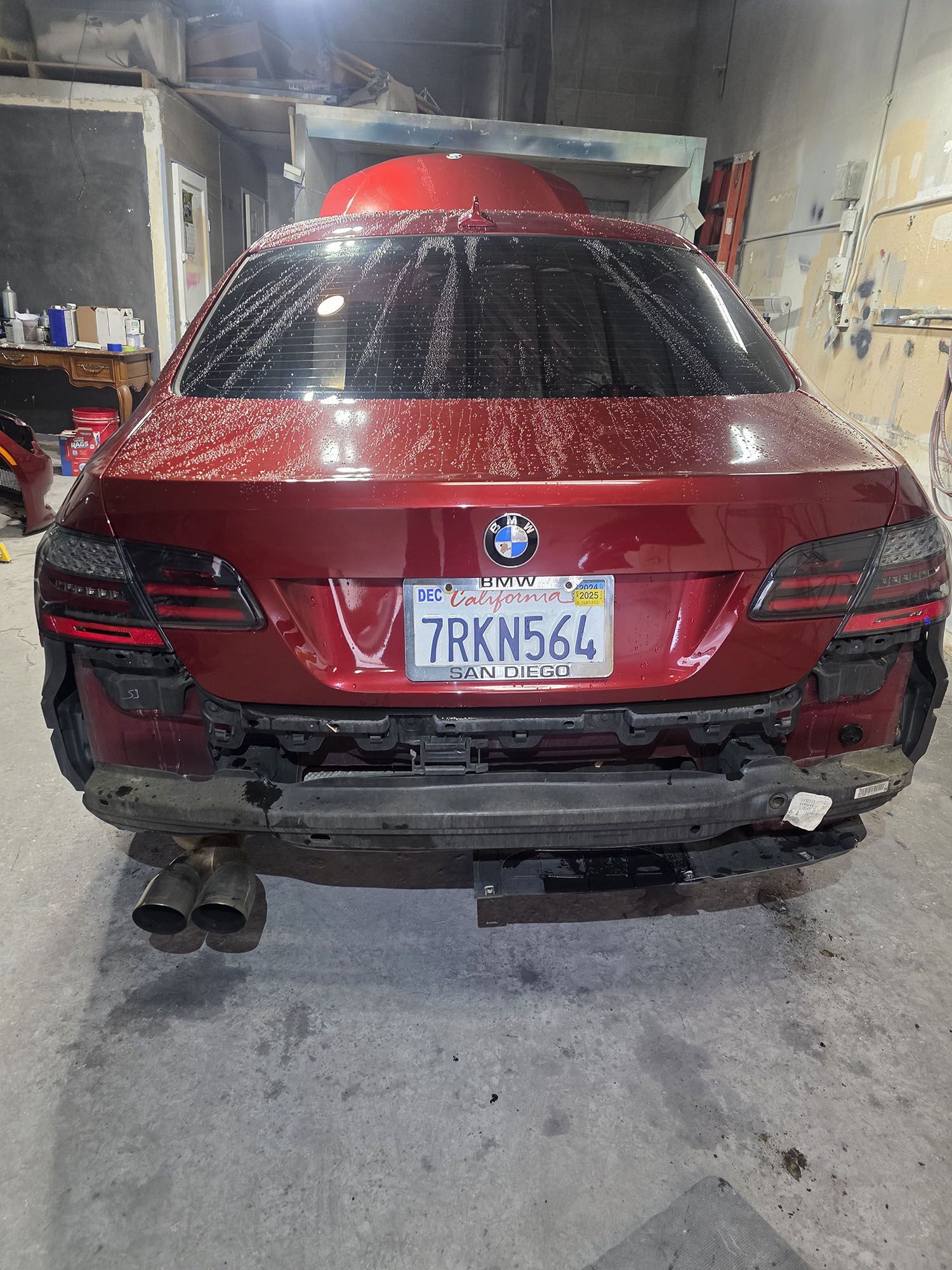 Red BMW SUV viewed from behind in a garage, with a wet rear window and license plate visible.