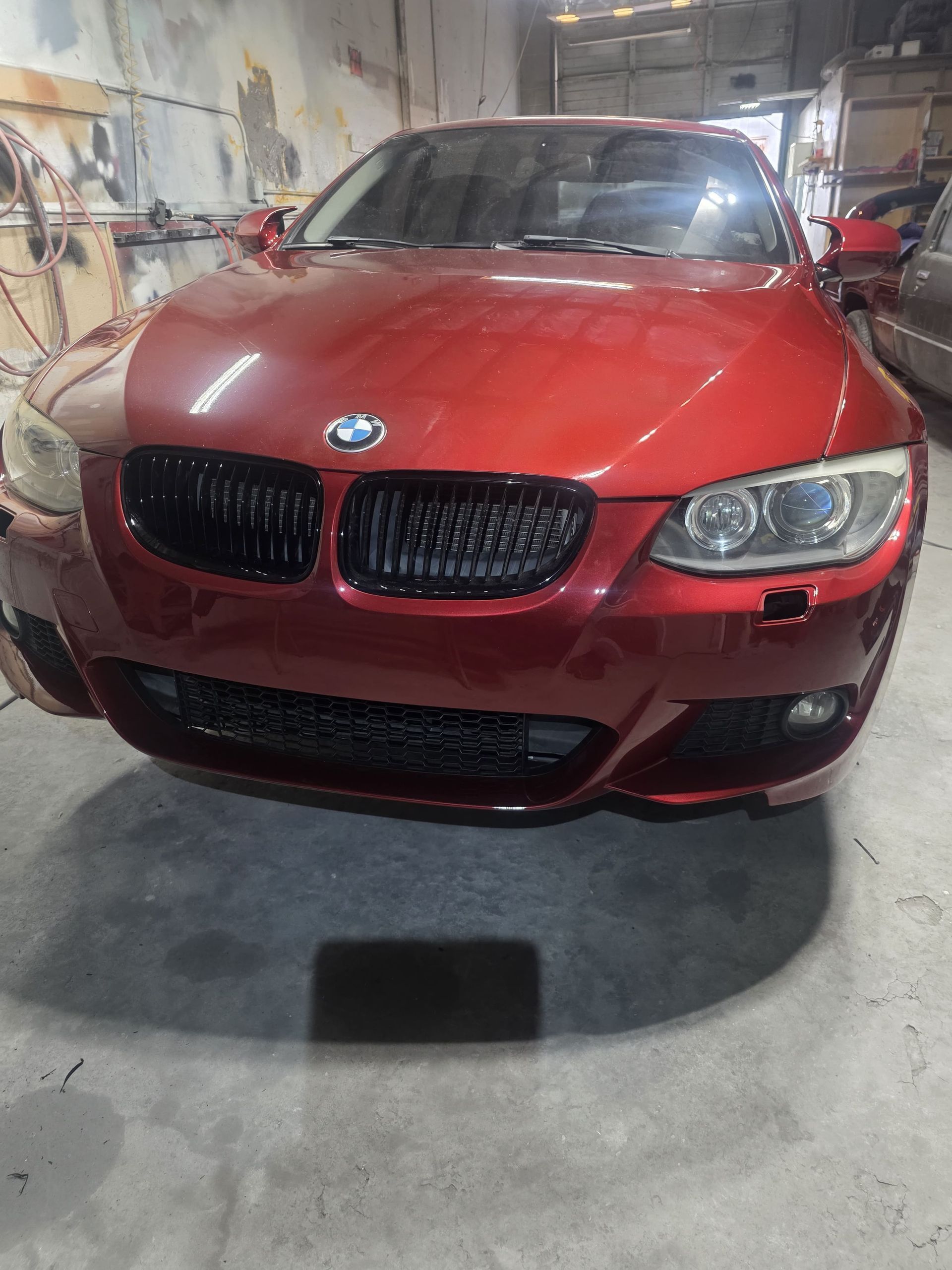 Red BMW sedan in a garage, viewed from the front.
