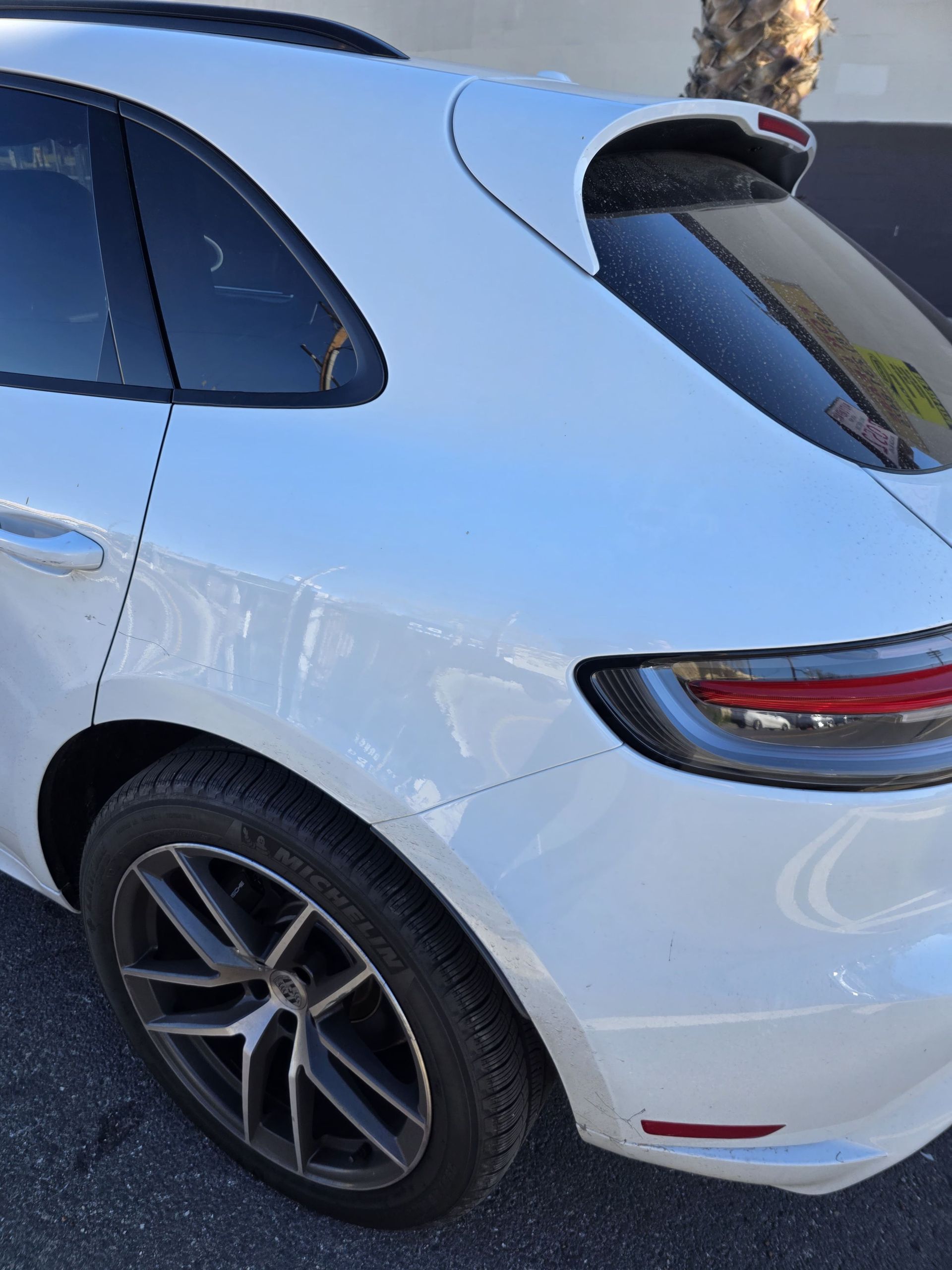 White SUV parked outdoors, rear side view with tinted windows and black alloy wheel.
