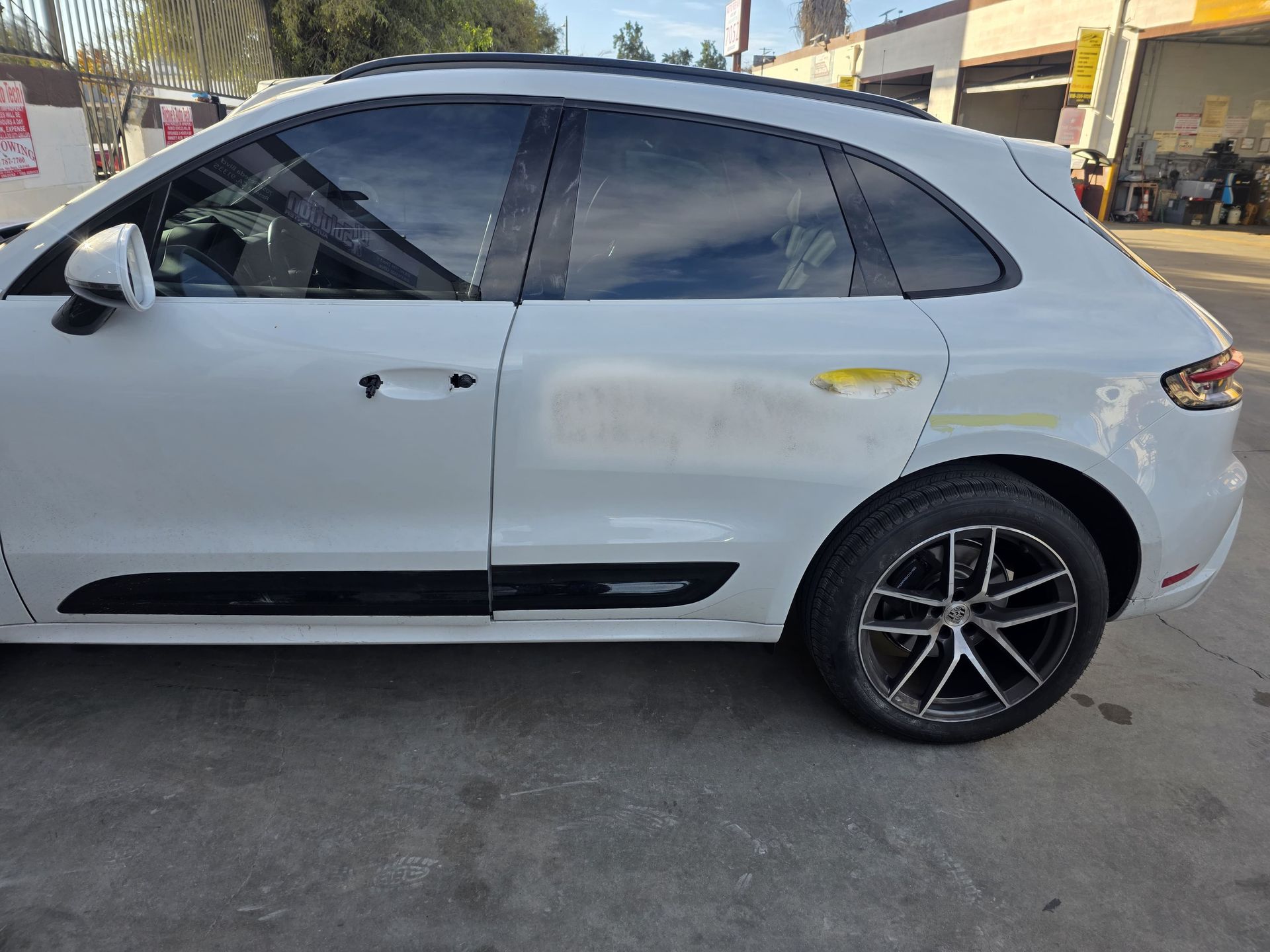 White sedan parked on a street, side view with tinted windows and black rims.
