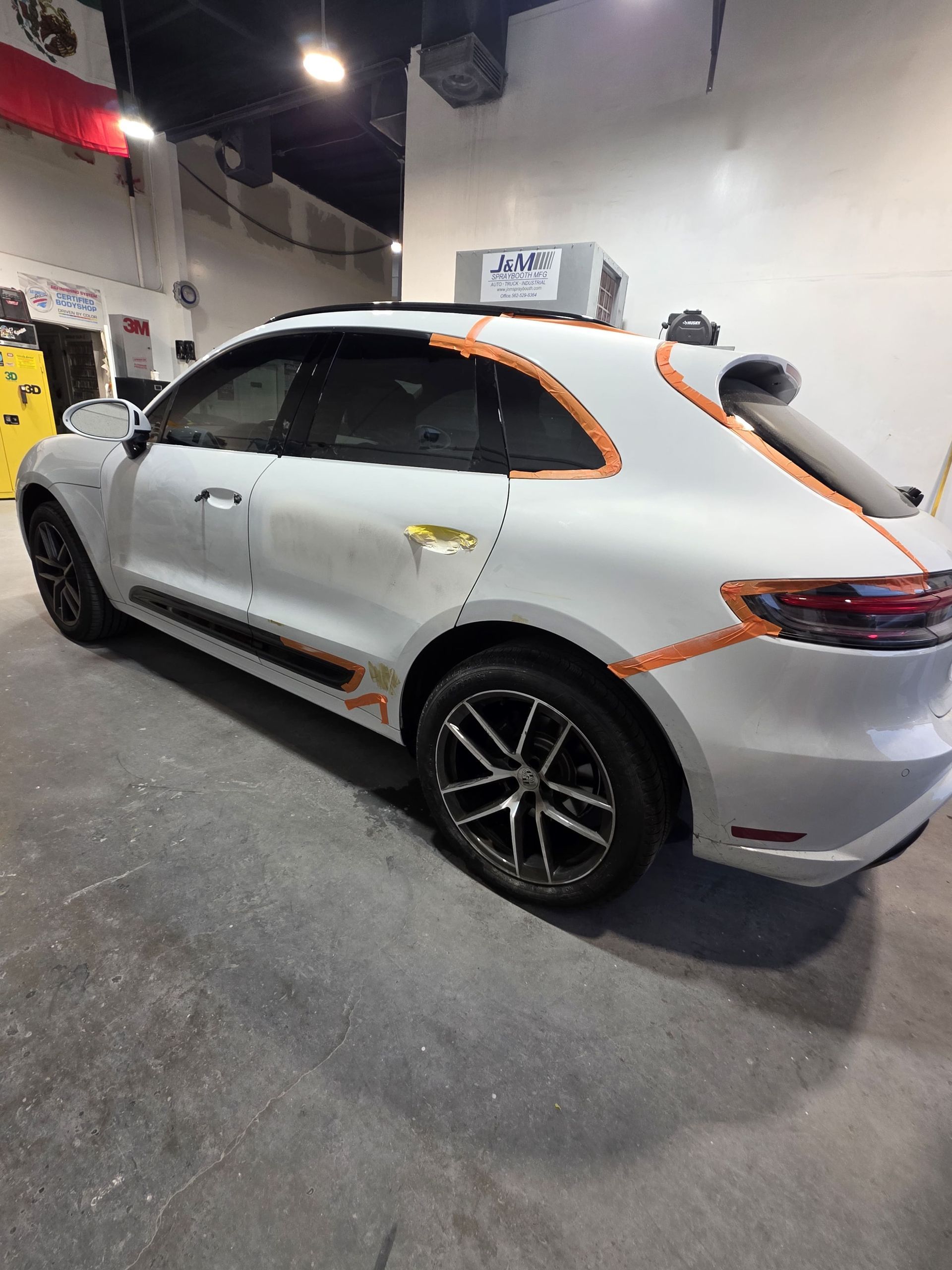 White SUV with orange trim in a garage, shown from the rear side.