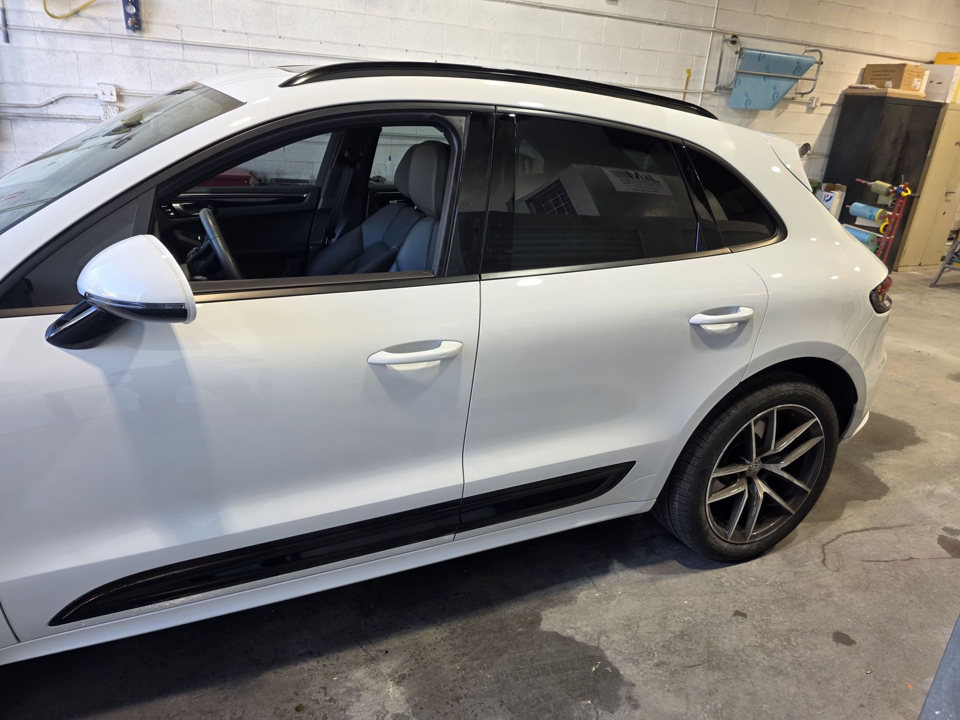 White SUV parked indoors in a garage, side view with tinted windows and black trim