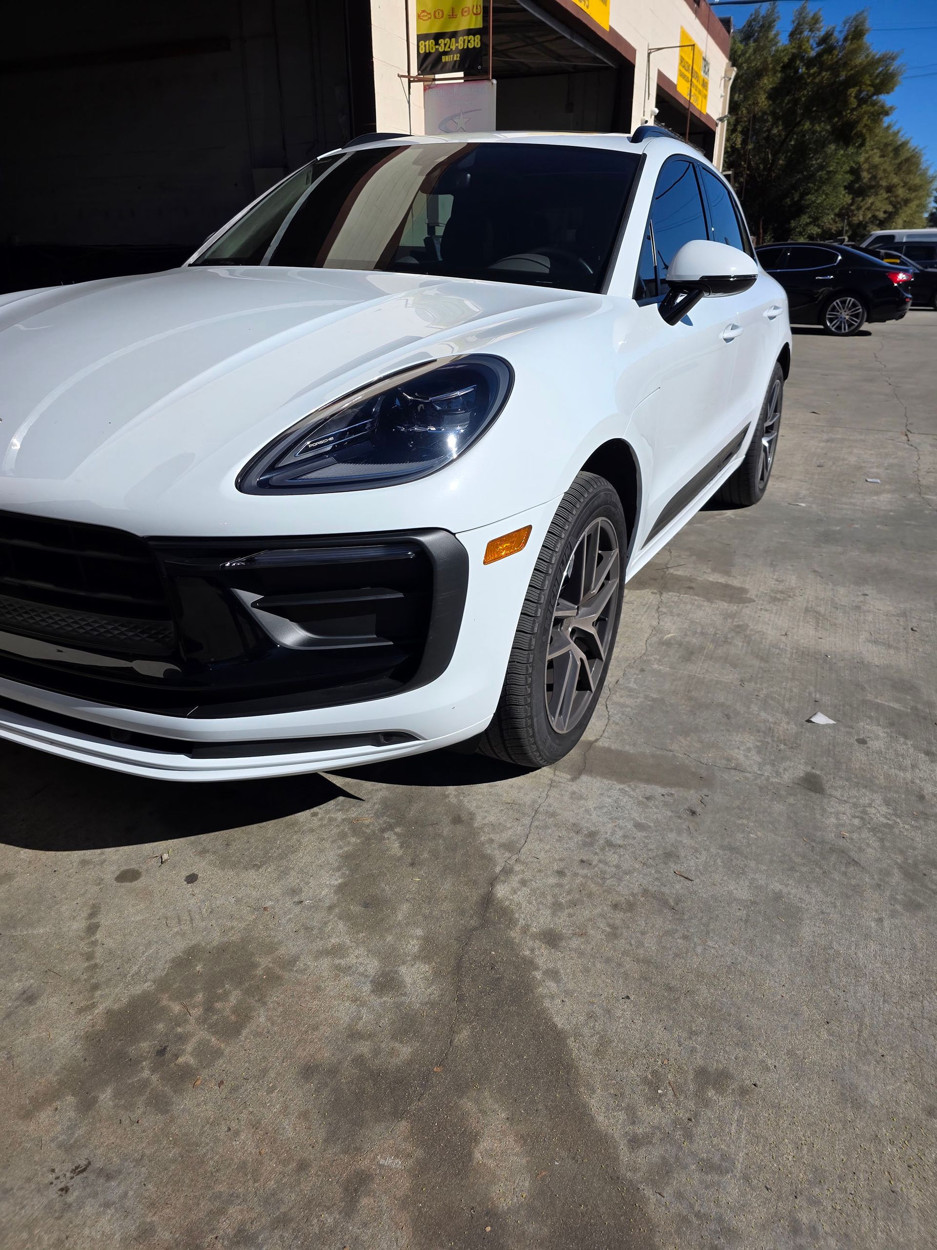 White Porsche SUV parked outside a building in bright sunlight