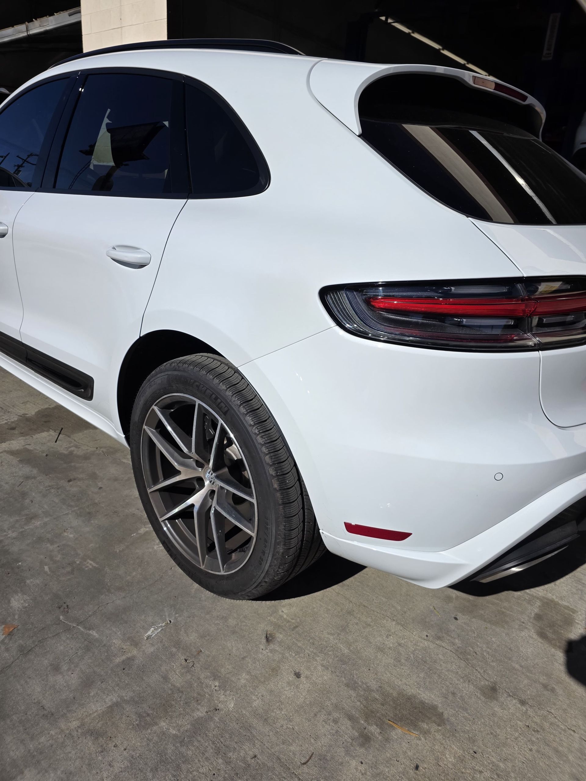 White SUV parked on concrete, rear side view with tinted windows and alloy wheels