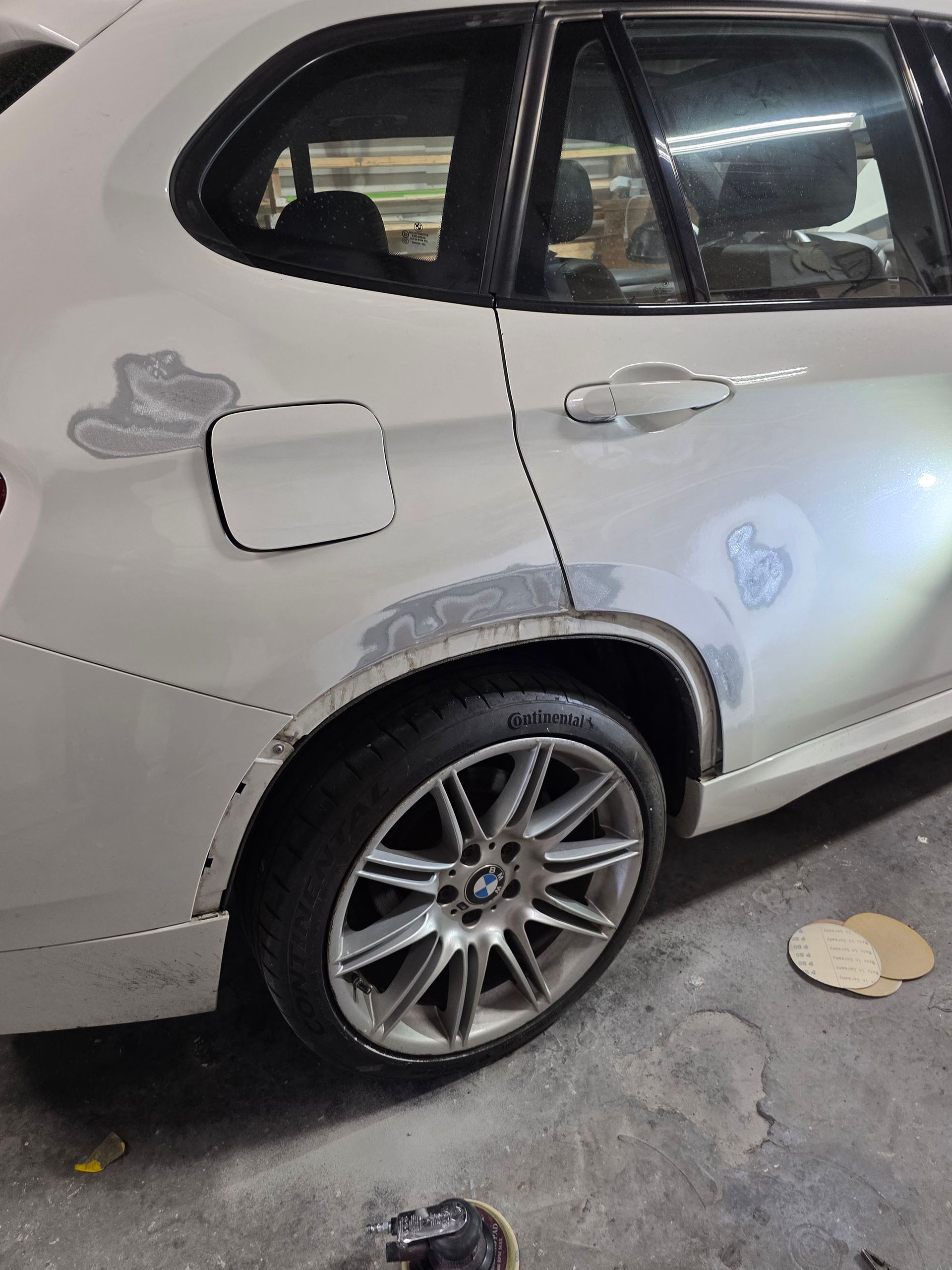 Silver car parked on a street, showing rear side damage and scuffed body panels.