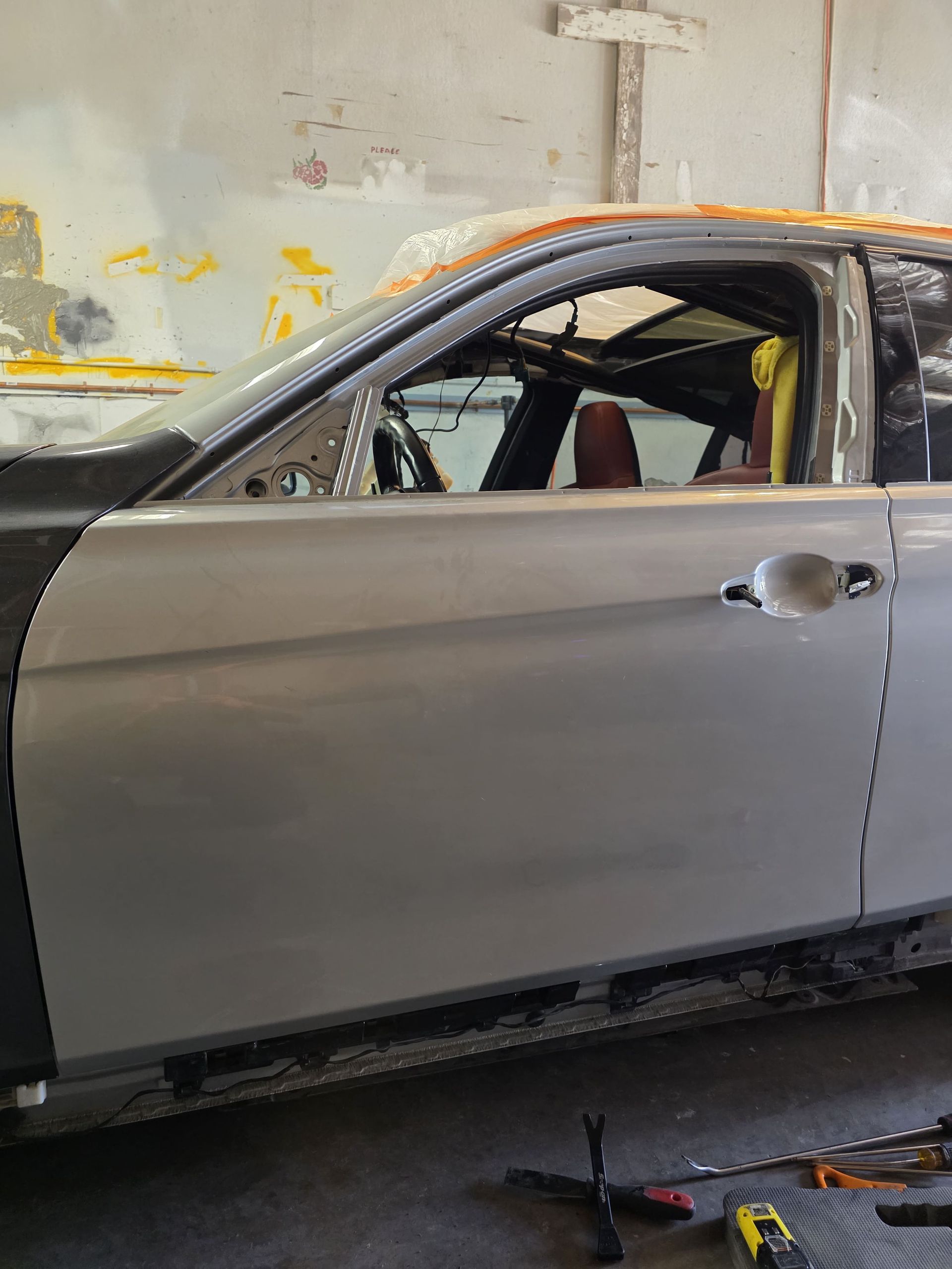 Silver car door being repaired in a workshop, with tools on the floor and window removed