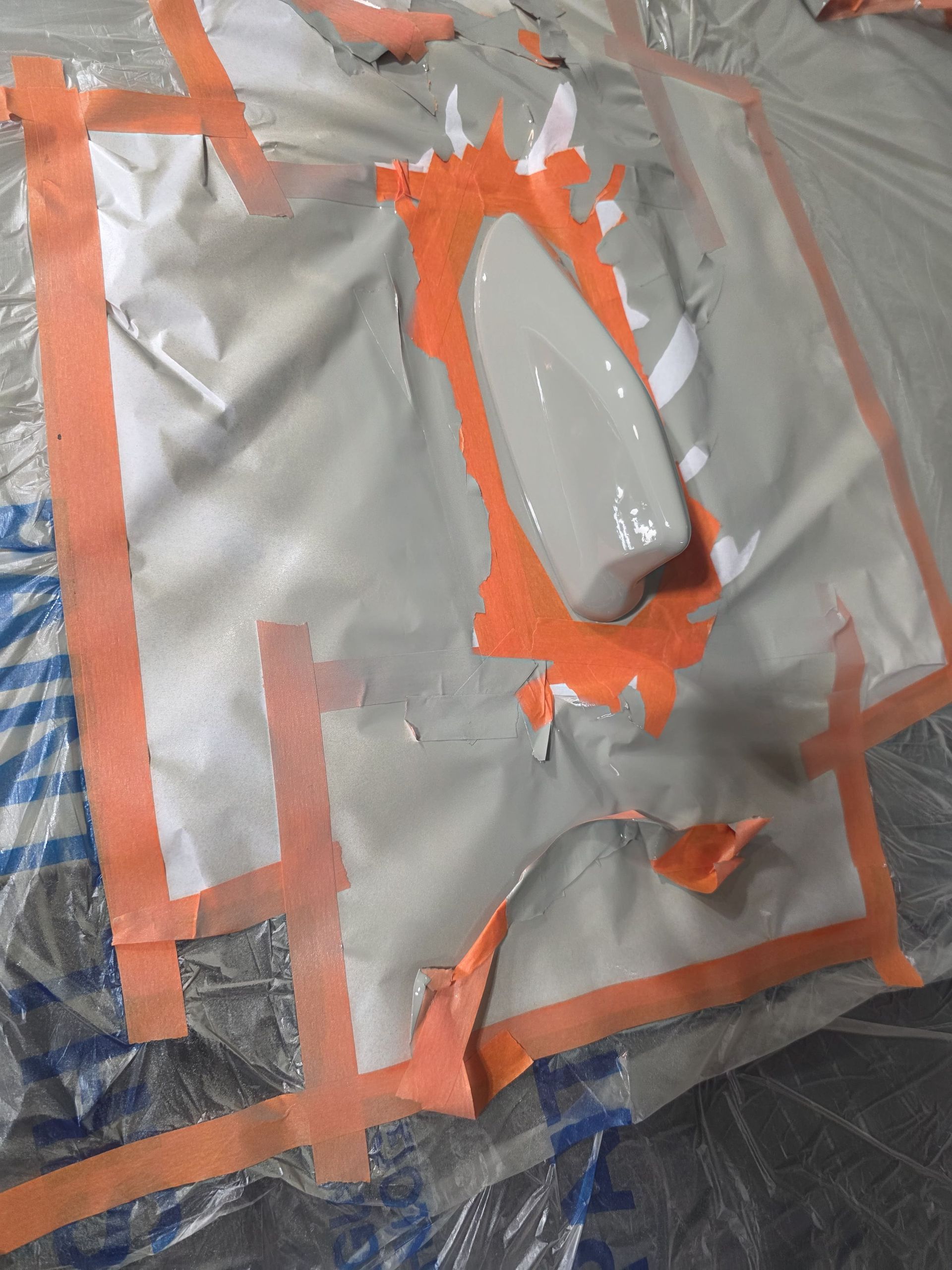 Silver and orange taped plastic surface with a raised tear or patch in the center.