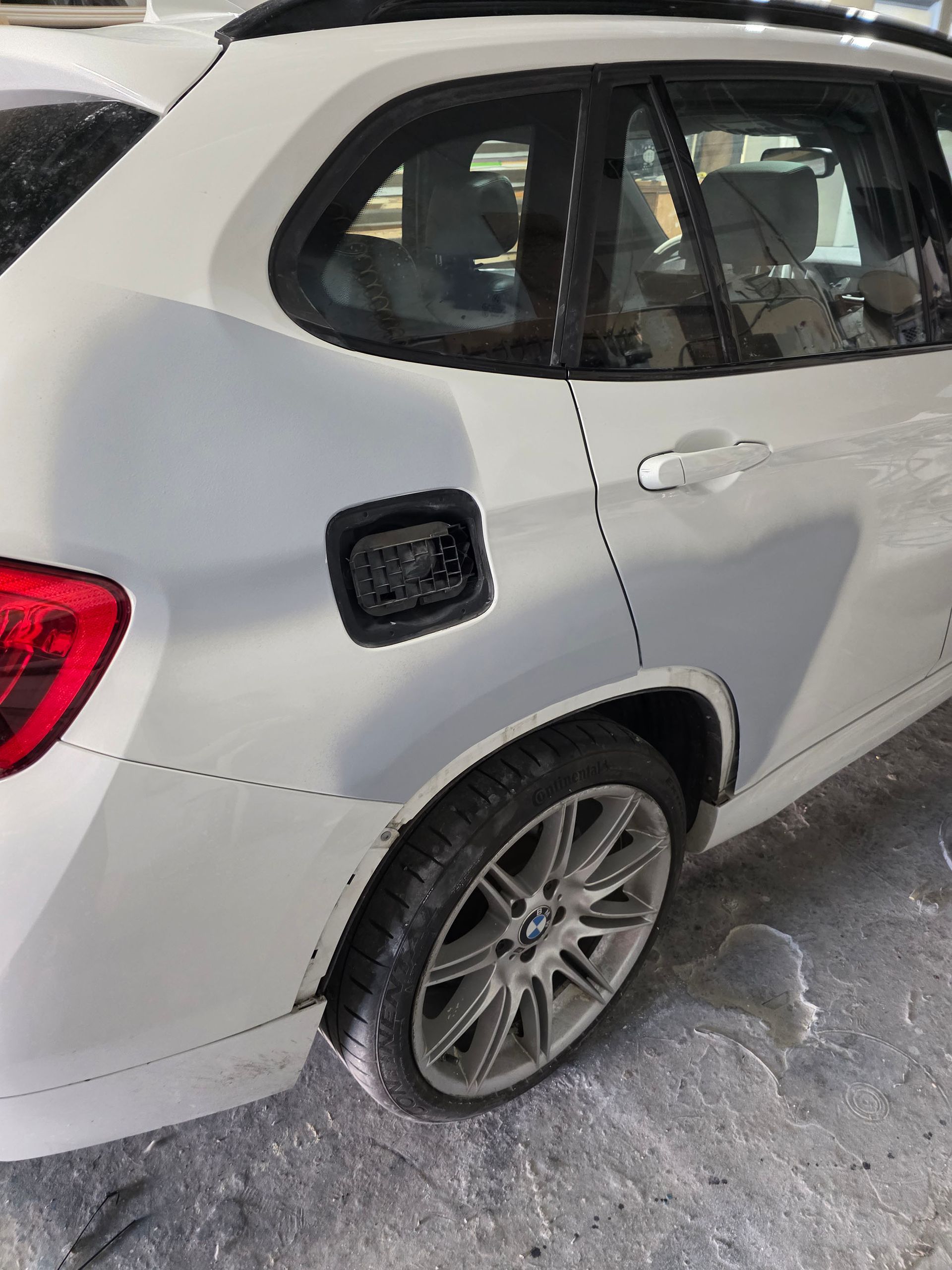White SUV parked in a garage, showing the rear side and wheel close-up