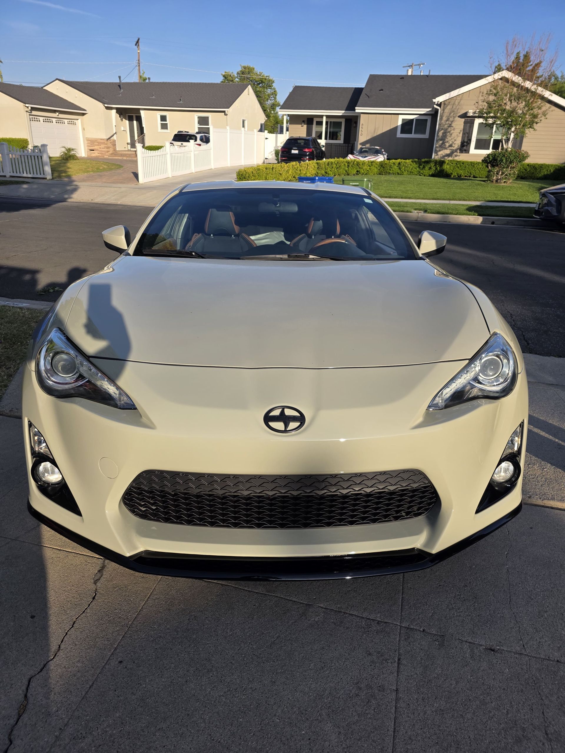 Front view of a white sports coupe parked on a suburban street in daylight