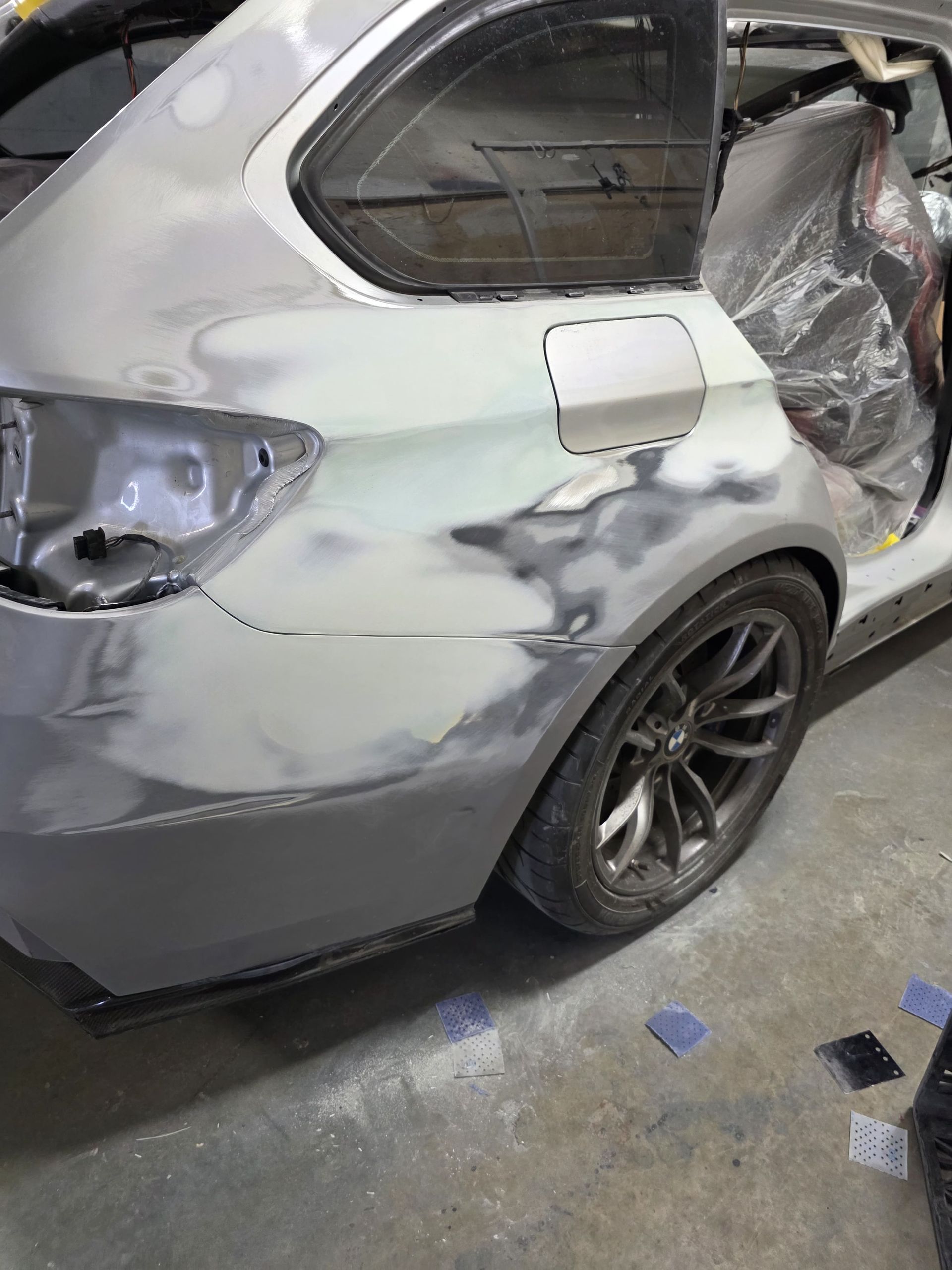 Damaged silver SUV with scraped rear quarter panel and dented side, parked in a workshop