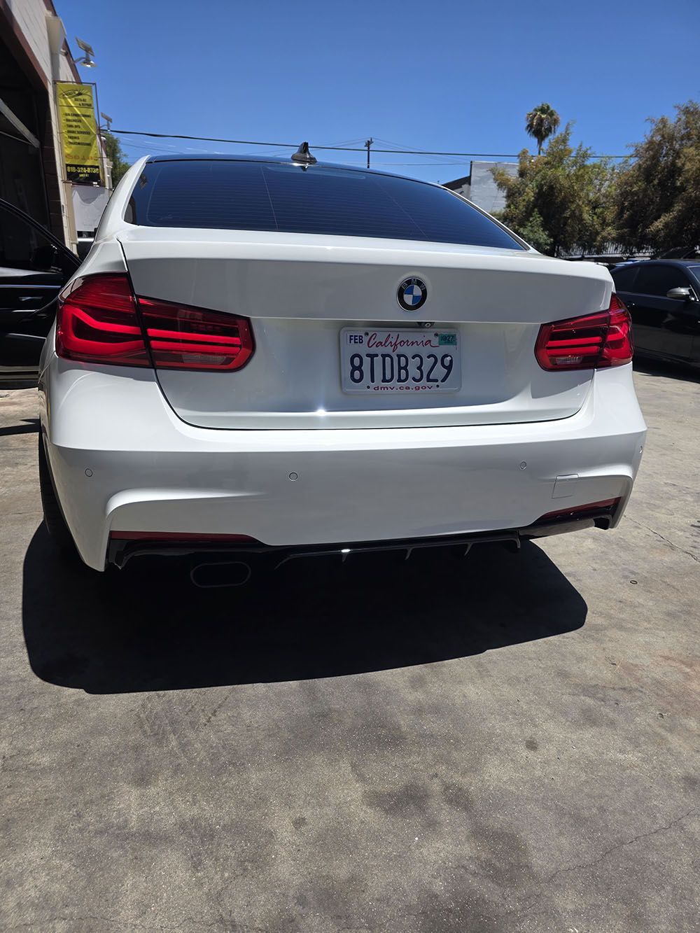 White BMW sedan parked outdoors, rear view with visible license plate and tinted windows
