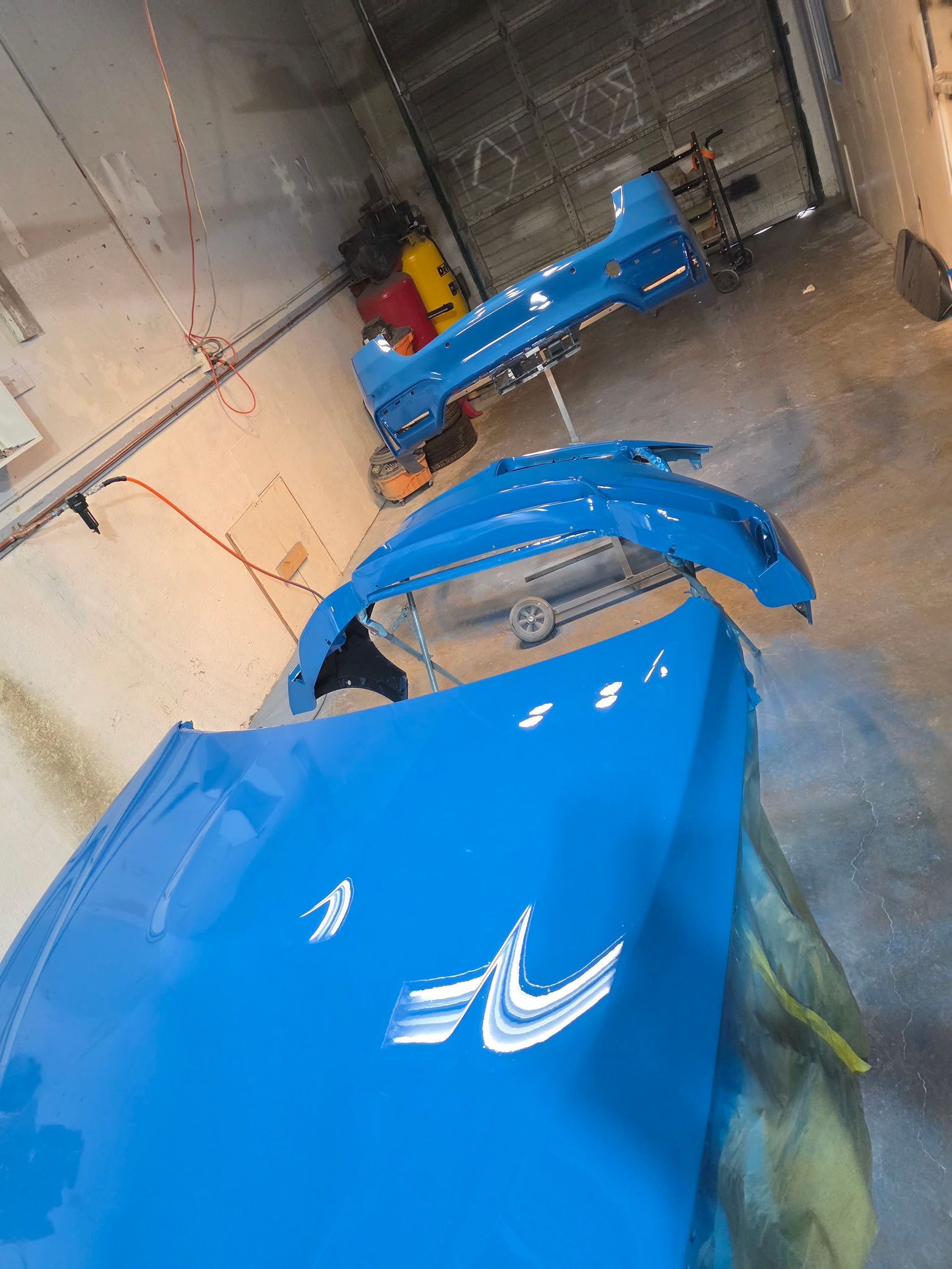 Blue industrial equipment in a storage area, with a yellow machine at the back.