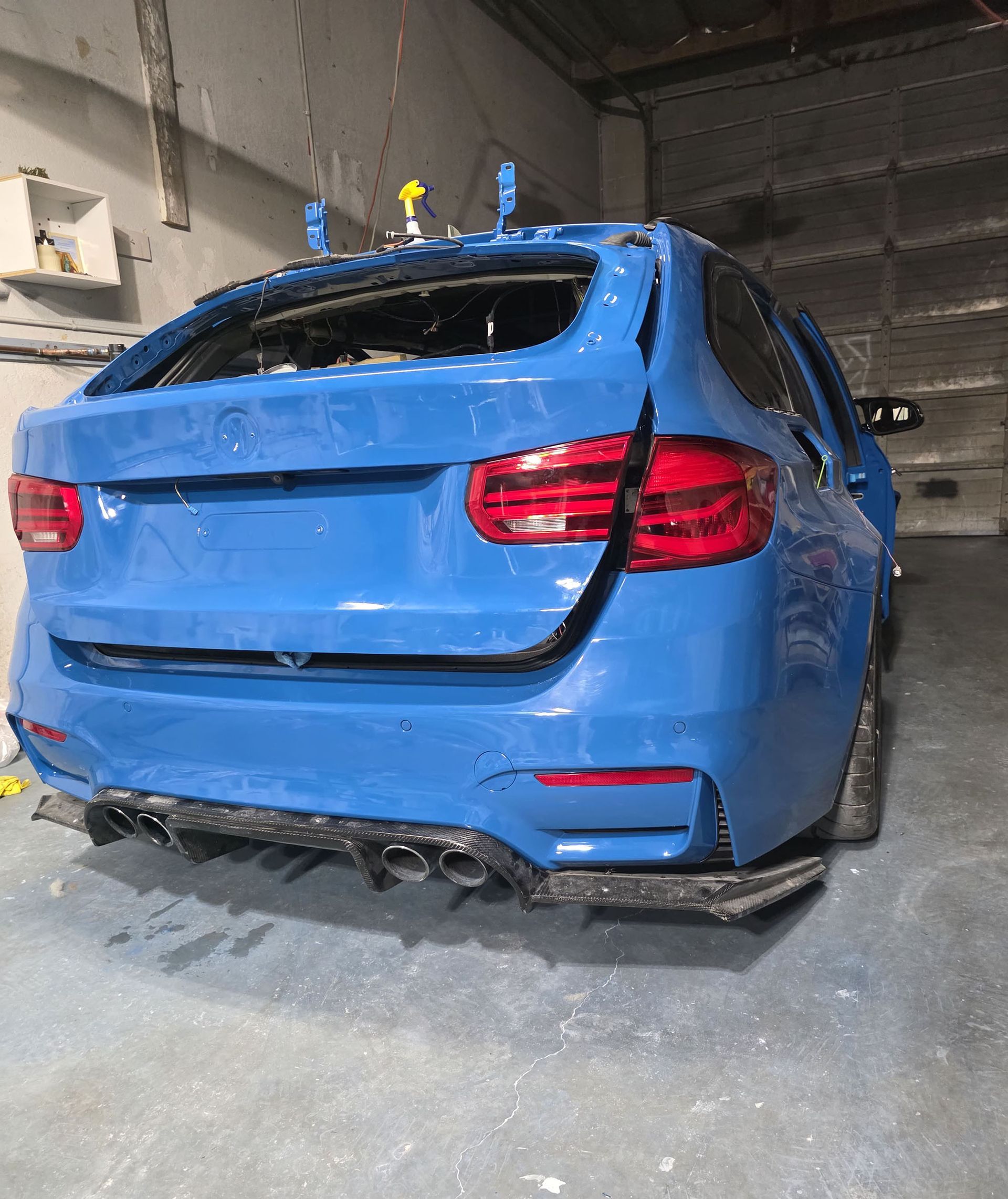 Damaged blue SUV with crumpled rear end in an indoor garage