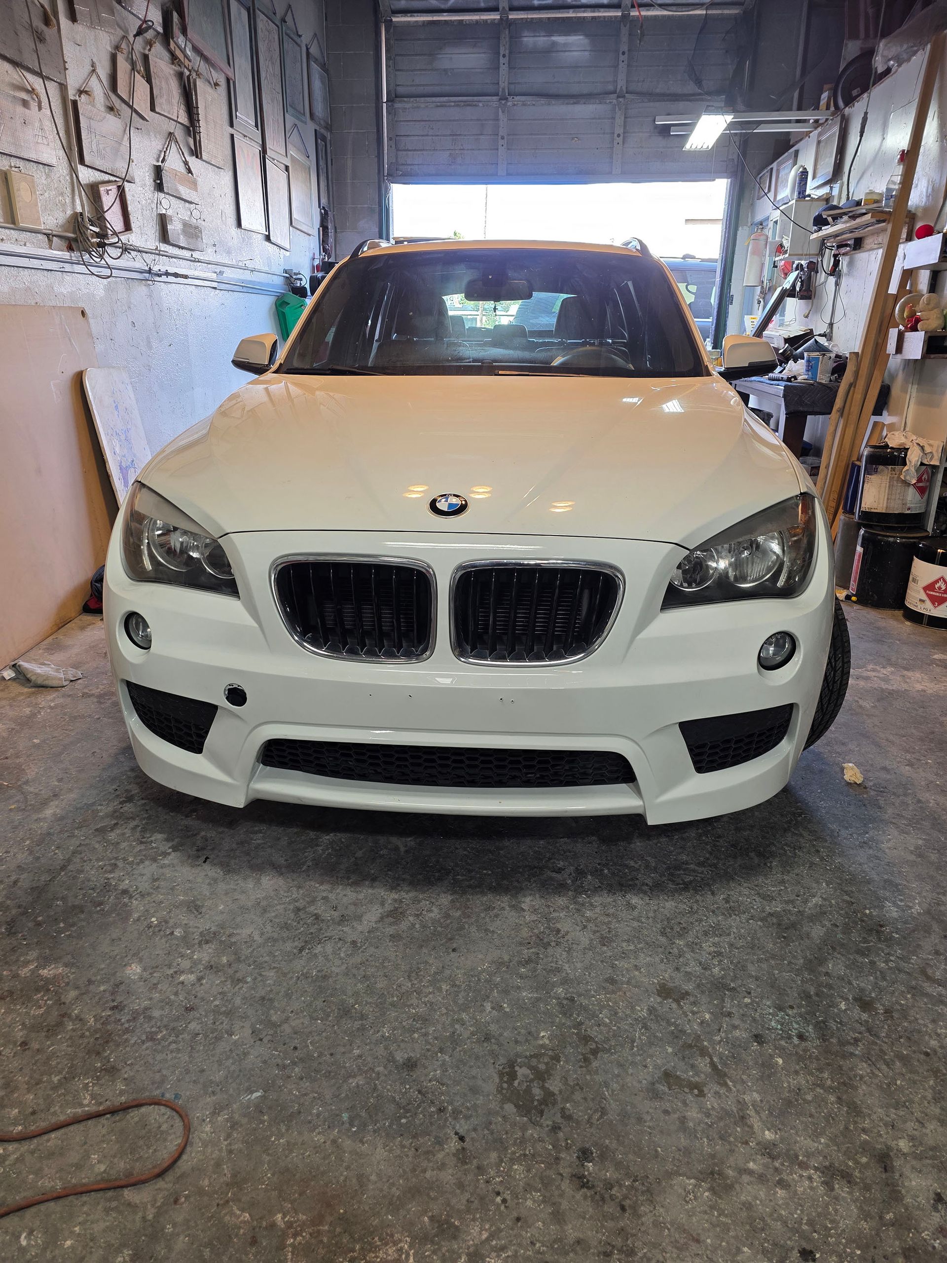White BMW SUV parked inside a garage, viewed from the front.
