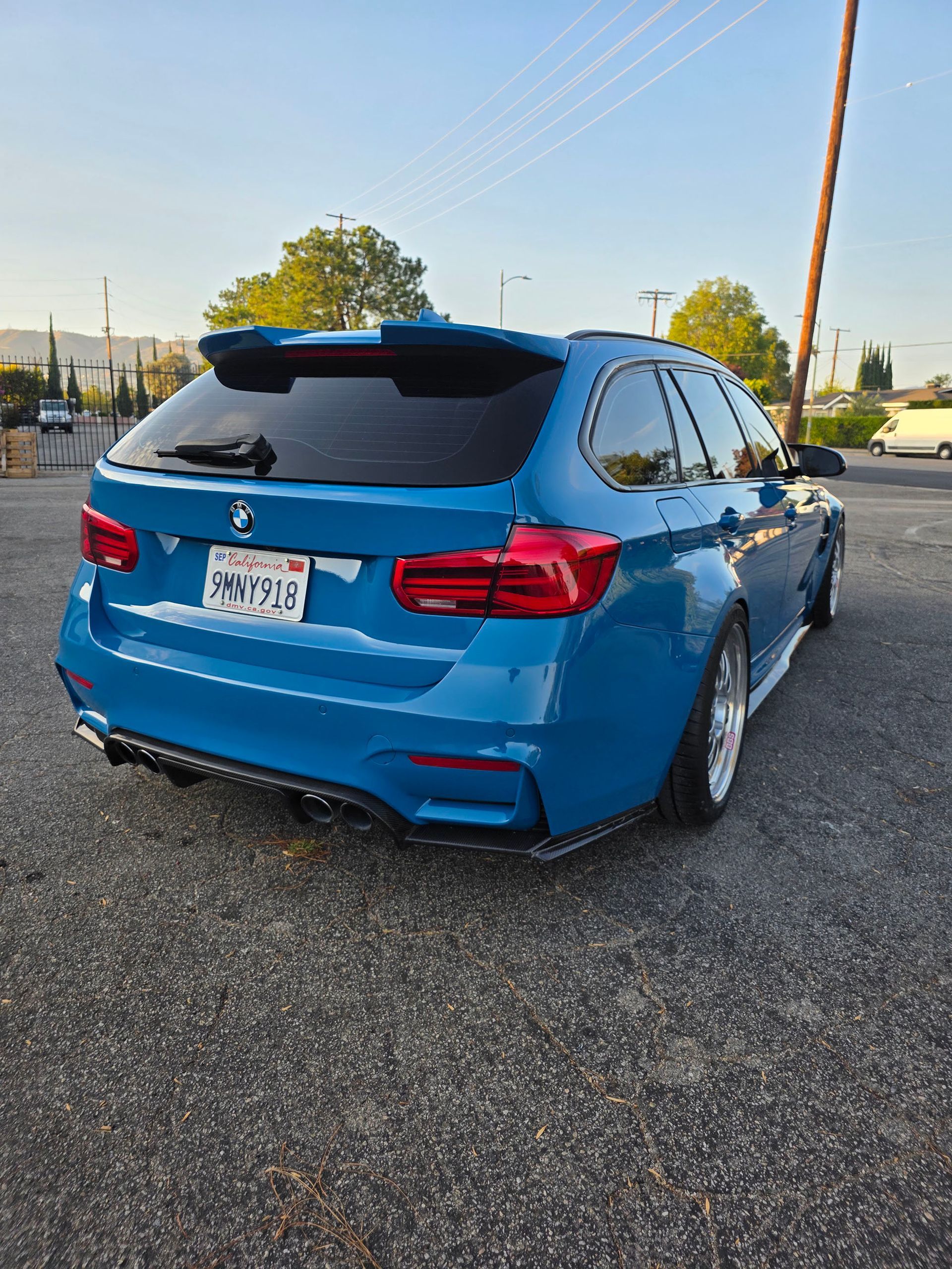 Blue SUV parked on gravel at sunset, rear three-quarter view